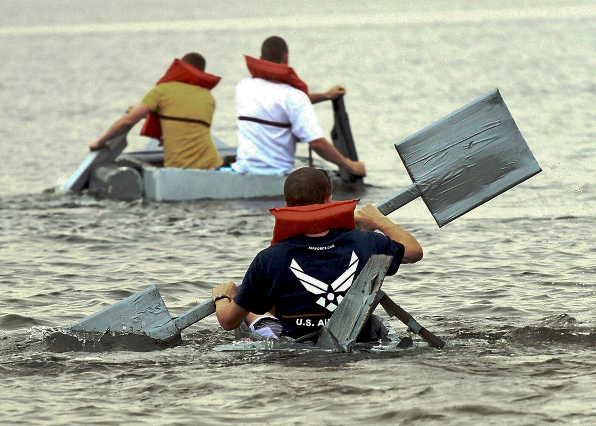 Christopher Berglund tries hard to keep up with Team Dinstar, the winners of the cardboard boat regatta race March 31 at Eglin Air Force Base, Fla.  Eight teams competed at this year's race.  (Courtesy photo/Senior Airman Mitchell Forde)