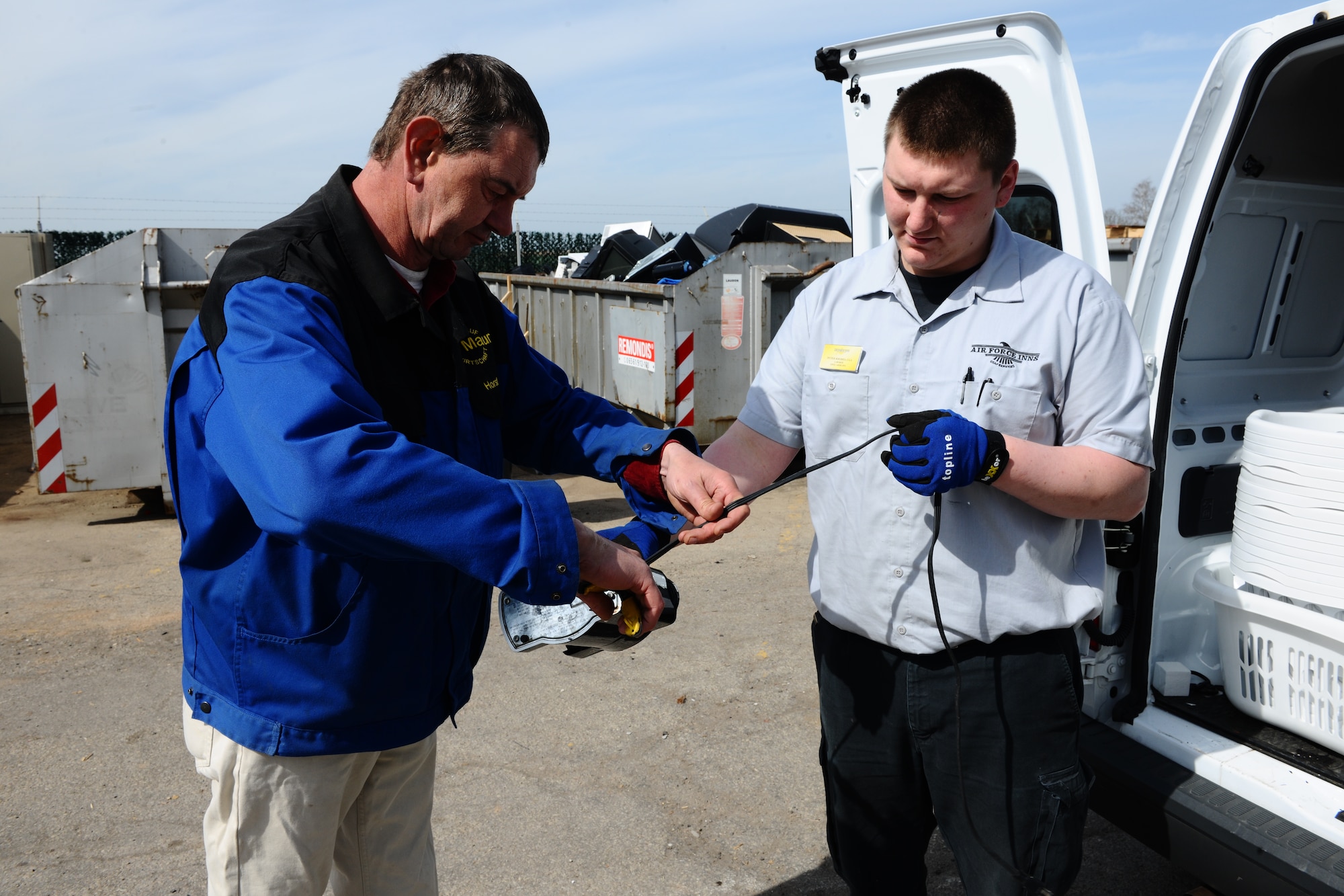 SPANGDAHLEM AIR BASE, Germany – Horst Thiel, left, 52nd Civil Engineer Squadron Recycling Center manager, cuts the power cord from a coffee maker while Peter Rhodes, Air Force Inn custodial worker, holds the appliance at the recycling center here April 2 so the cord can be recycled separately. Power cords are recycled separately from electronic items because the cords are recycled only for the metal they contain. The recycling center gives base members a solution for unwanted reusable wastes ranging from paper to half-full aerosol cans. The center is open 11 a.m. – 5 p.m. Monday, Tuesday and Friday; 9 a.m. – 6 p.m. Thursday; and 9 a.m. – 4 p.m. Saturday. (U.S. Air Force photo by Airman 1st Class Dillon Davis/Released)