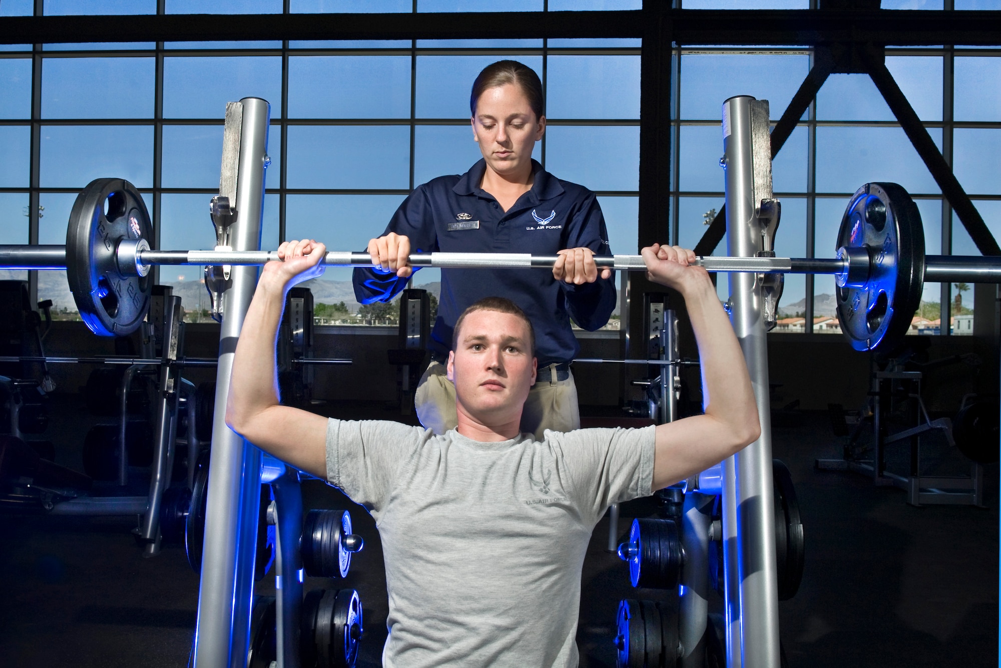 U.S. Air Force Senior Airman Whitney Massey, 99th Force Support Squadron services journeyman, spots Airman 1st Class Benjamin Hurst on the free weights at the Warrior Fitness Center April 2, 2012, at Nellis Air Force Base, Nev. The state-of-the-art facility's strength training equipment offers Magnum, Nautilus Hammer Strength, Free Motion and Hampton Rubber Bumper Plates training.  (U.S. Air Force photo by Lawrence Crespo)