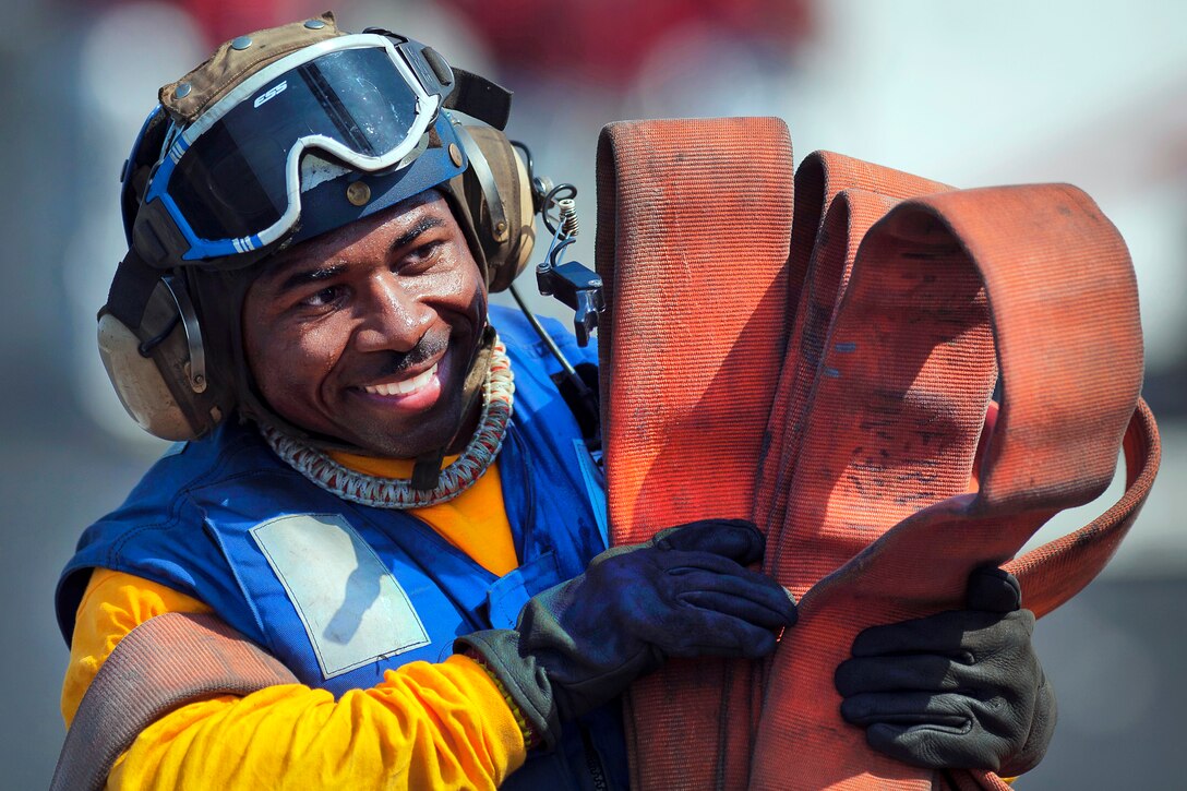 U.S. Navy Petty Officer 1st Class Quinton Jones stows hoses after flight deck firefighting