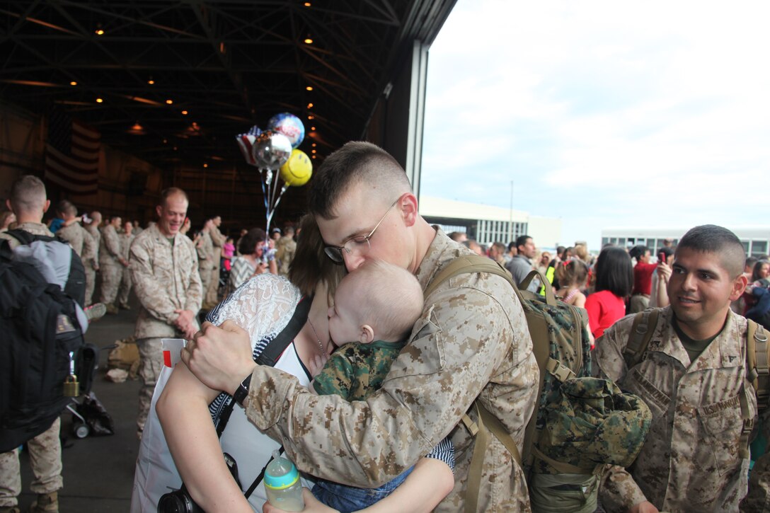 Lance Cpl. Curtis W. Schultz, an avionics mechanic with Marine Tactical Electronic Warfare Squadron 1, hugs his wife, Mariah, and son, Owen, after returning from a seven-month deployment to Italy and Afghanistan during the VMAQ-1, homecoming outside the squadron's hangar April 4. More than 120 Marines and Sailors returned from deployment after being relieved by VMAQ-2 on March 26.