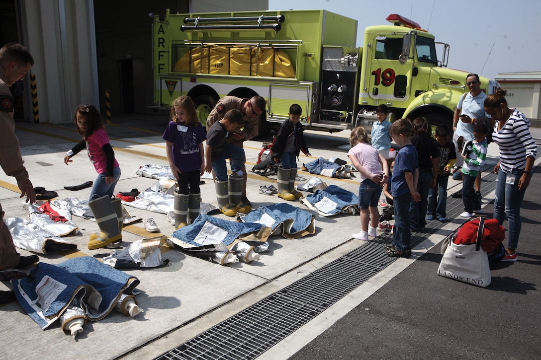 Students from Bechtel Elementary School don bunker gear during an Aircraft Rescue and Firefighting demonstration on Marine Corps Air Station Futenma April 4. Bunker gear is protective equipment used by firefighters while battling aircraft fires. The students learned when, why and how the bunker gear is worn.