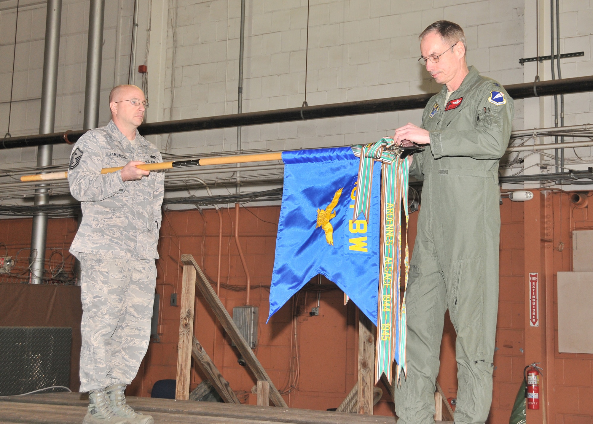 131st Bomb Wing Commander Col. Greg Champagne affixes the Air Force Outstanding Unit Award streamer to the 131st Bomb Wing unit flag while Master Sgt. David Zambruski stands by, Feb 11. The 131st was awarded this high honor for exceptionally meritorious service from 1 June 2008 to 31 May 2010. (Photo by Senior Master Sgt. Mary-Dale Amison)