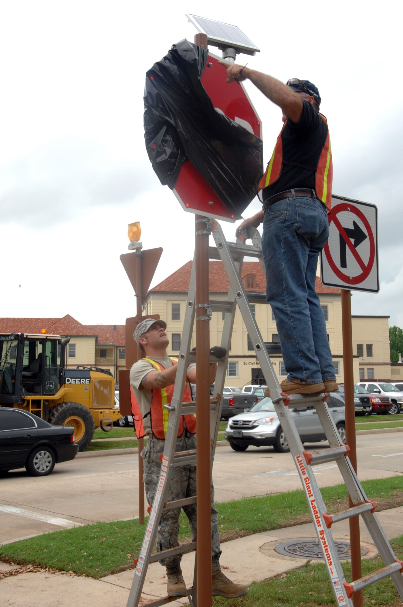 Staff Sgt. Davin Stege, 2nd Civil Engineer Squadron, stabilizes the ladder for Jerry Jacobson, 2 CES, on Barksdale Air Force Base, La., April 3. Stege and Jacobson installed a solar panel on the newly placed stop signs on the intersection of Davis Avenue West and Barksdale Boulevard West. (U.S. Air Force photo/Airman 1st Class Joseph A. Pagán Jr.)(RELEASED)