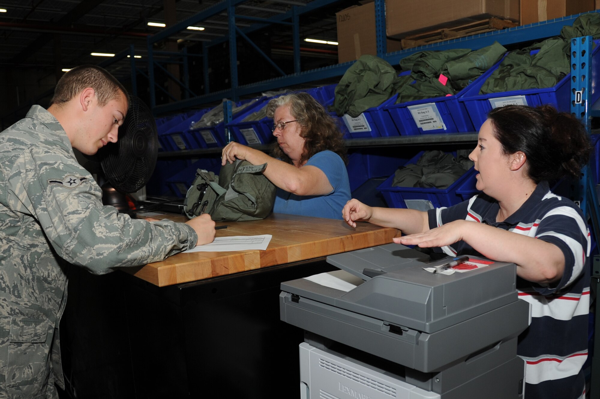 Airman Kenny Corcoran, 81st Logistics Readiness Squadron, signs a hand receipt for a gas mask given to him by Tina Lancaster while Elizabeth O’Dea makes copies of hand receipts during a deployment exercise March 29, 2012, inside the 81st Logistics Readiness Squadron warehouse at Keesler Air Force Base, Miss.  (U.S. Air Force photo by Kemberly Groue)