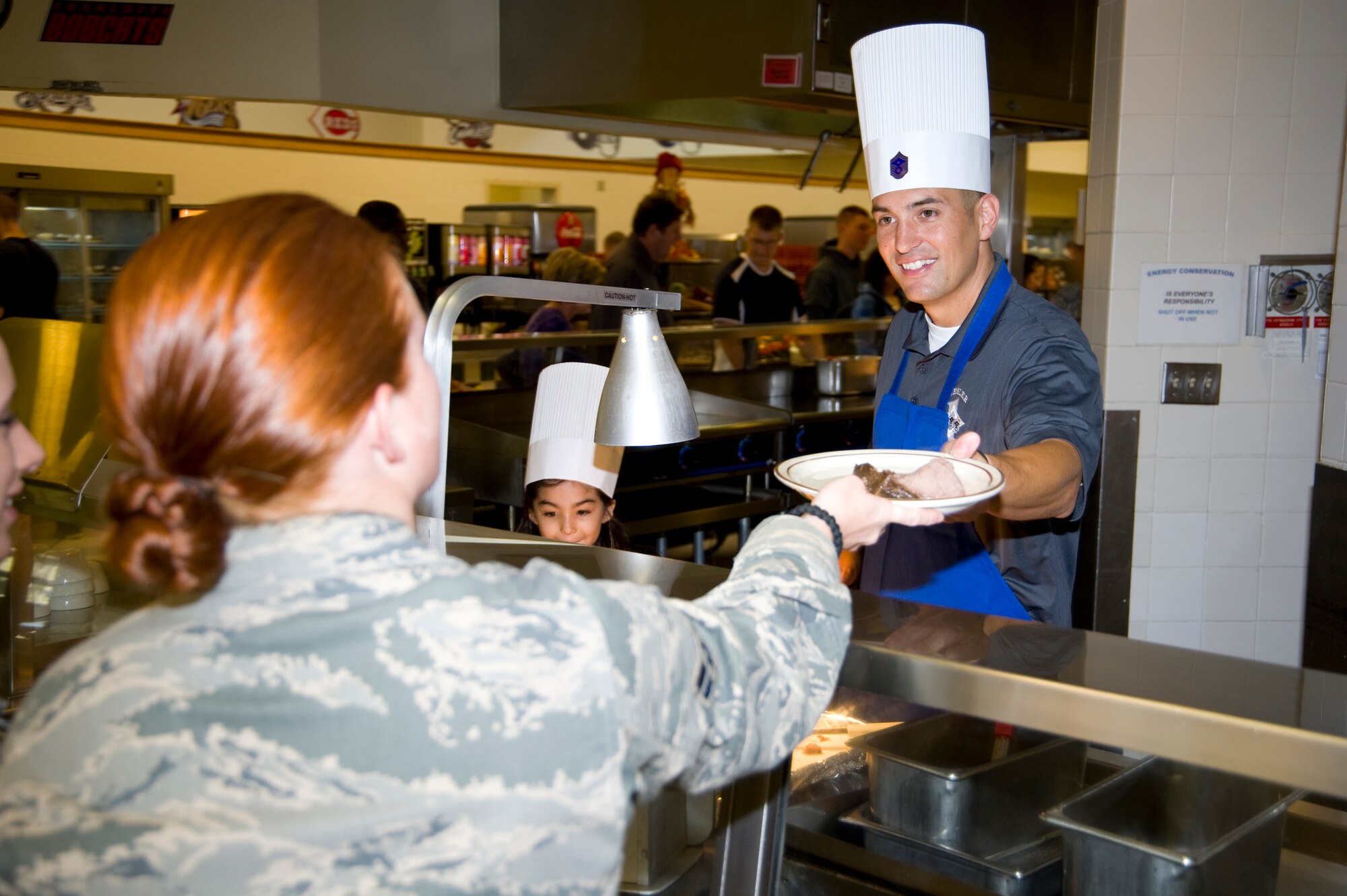 Senior Master Sgt. Joel Shepherd, 338th Training Squadron first sergeant, assisted by his daughter, Leilani, 7, serves roast beef to Airman 1st Class Madi Nichols, 336th Training Squadron, during Thanksgiving lunch Nov. 24, 2011, at the Magnolia Dining Facility, Keesler Air Force Base, Miss.  Base leaders serve the Thanksgiving meal each year to boost morale among Airmen who can’t share the holiday with their families.  A first sergeant’s job is to take care of his or her people, they achieve this through participating in base events and interacting directly with their Airmen. (U.S. Air Force photo by Adam Bond)
