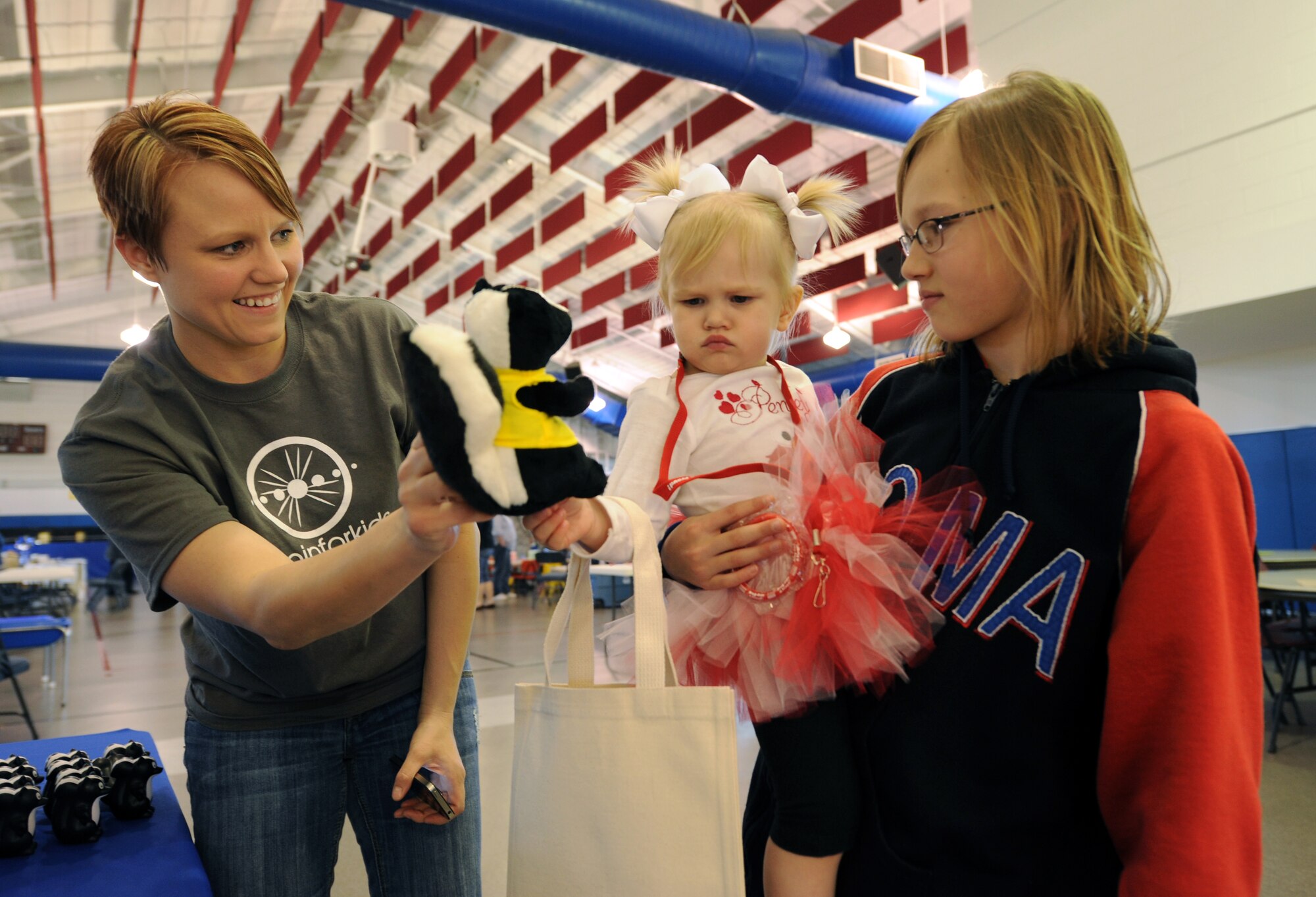Penley Zika, 19 months old, frowns as her mom, Jessica, shows her the “Drugs Stink” skunk at the Drug Demand Reduction Program table at the Beautiful Child Photo Shoot and Activity Fair on April 3, 2012, on Grand Forks Air Force Base, N.D. Also pictured is Penley’s older sister, 10-year-old Paisley Zika. (U.S. Air Force photo/Tim Flack)