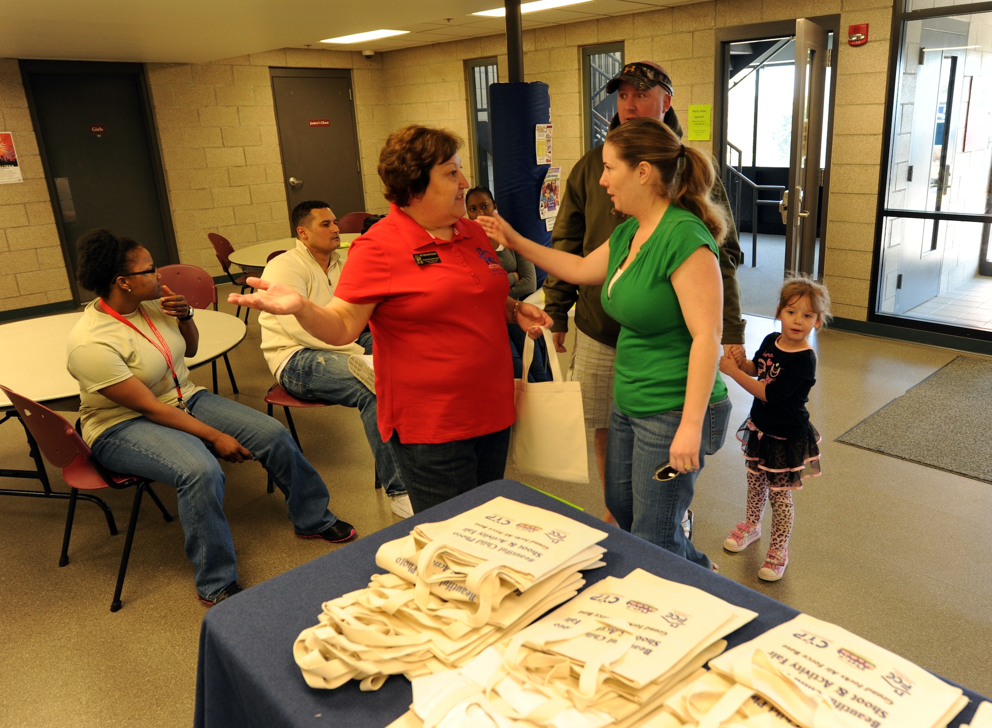 Pam Schumaker, Family Child Care coordinator with the Airmen and Family Readiness Center, welcomes Staff Sgt. Julane Bentley, her husband, Tech. Sgt. Kevin Bentley, and their 4-year-old daughter, Samantha, during the April 3, 2012, Beautiful Child Photo Shoot and Activity Fair on Grand Forks Air Force Base, N.D. (U.S. Air Force photo/Tim Flack)