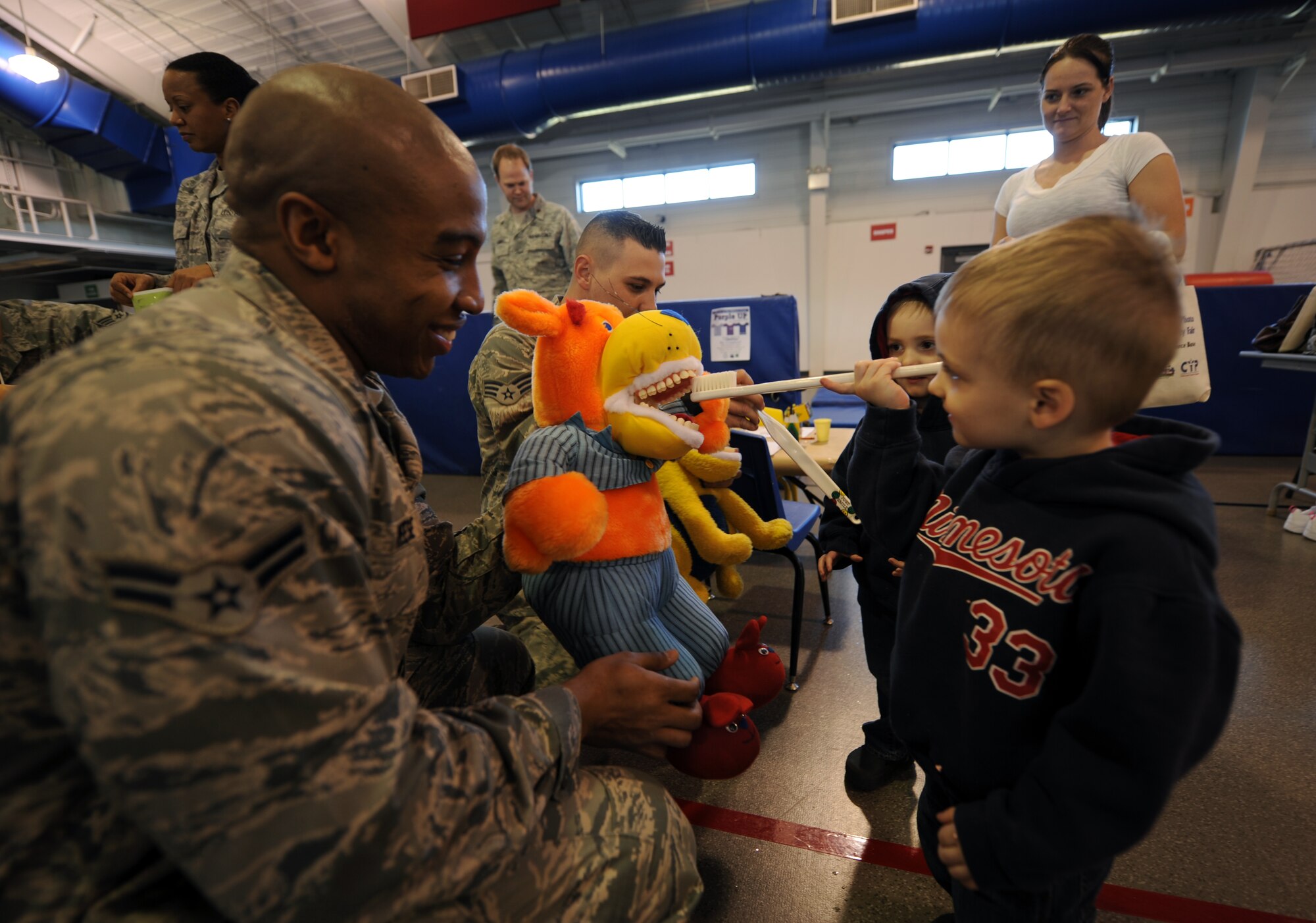 Airman 1st Class Robin Reese lets Lucas Thompson, 3, practice brushing teeth on a doll while his twin brother, William, looks on during the Beautiful Child Photo Shoot and Activity Fair on April 3, 2012, on Grand Forks Air Force Base, N.D. (U.S. Air Force photo/Tim Flack)