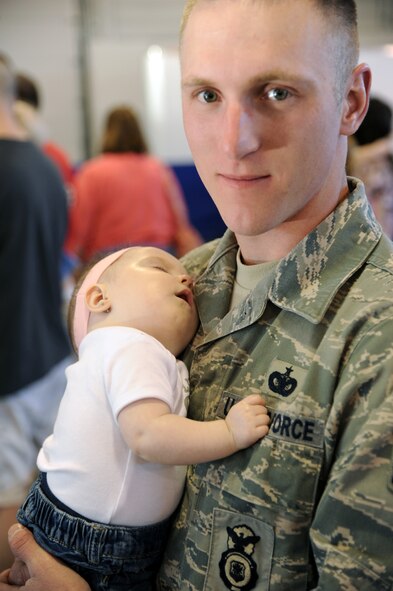 Staff Sgt. James Bredeson holds his 7-month-old daughter, Makenna, as she sleeps during the April 3, 2012, Beautiful Child Photo Shot and Activity Fair on Grand Forks Air Force Base, N.D. (U.S. Air Force photo/Tim Flack)