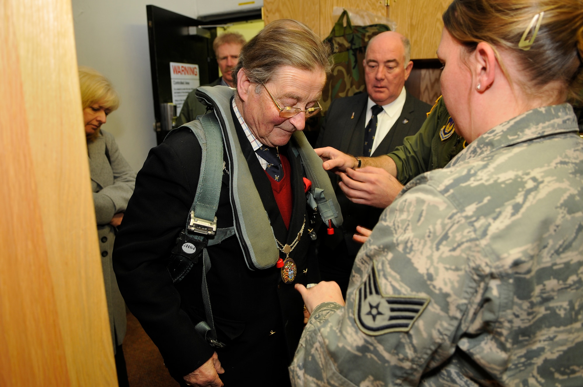 ROYAL AIR FORCE LAKENHEATH, England -- Staff Sgt. Jessica Jackson, right, 493rd Fighter Squadron aircrew flight equipment craftsman, helps The Worshipful The Mayor of St. Edmundsbury, Councillor Christopher Spicer, try on a PCU-15/P Torso Harness during his tour through the 493rd FS April 2, 2012.  Councillor Spicer toured the 493rd FS facilities to learn more about the history of the unit, to meet with the Airmen and to try on equipment from the life support section.  (U.S. Air Force photo by Staff Sgt. Connor Estes)