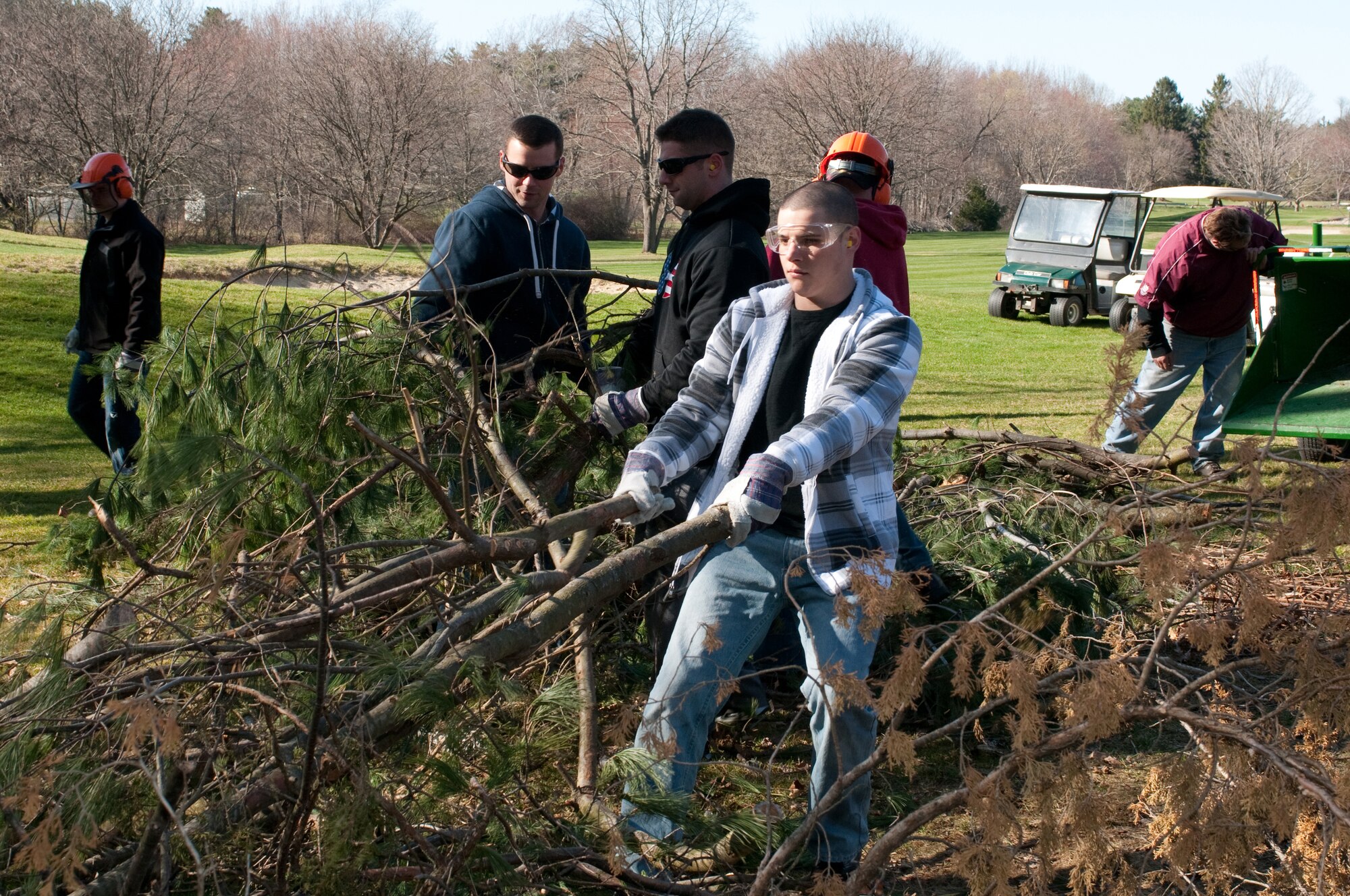 HANSCOM AIR FORCE BASE, Mass. -- Airman 1st Class Ryan Springer (front), along with other volunteers, move brush to a wood chipper that will be recycled as mulch around the Patiort Golf Course March 27. Volunteers from the Patriot Enlisted Association helped with a project to clean up the golf course and prepare it for opening day April 6. (U.S. Air Force Photo by Mark Herlihy)
