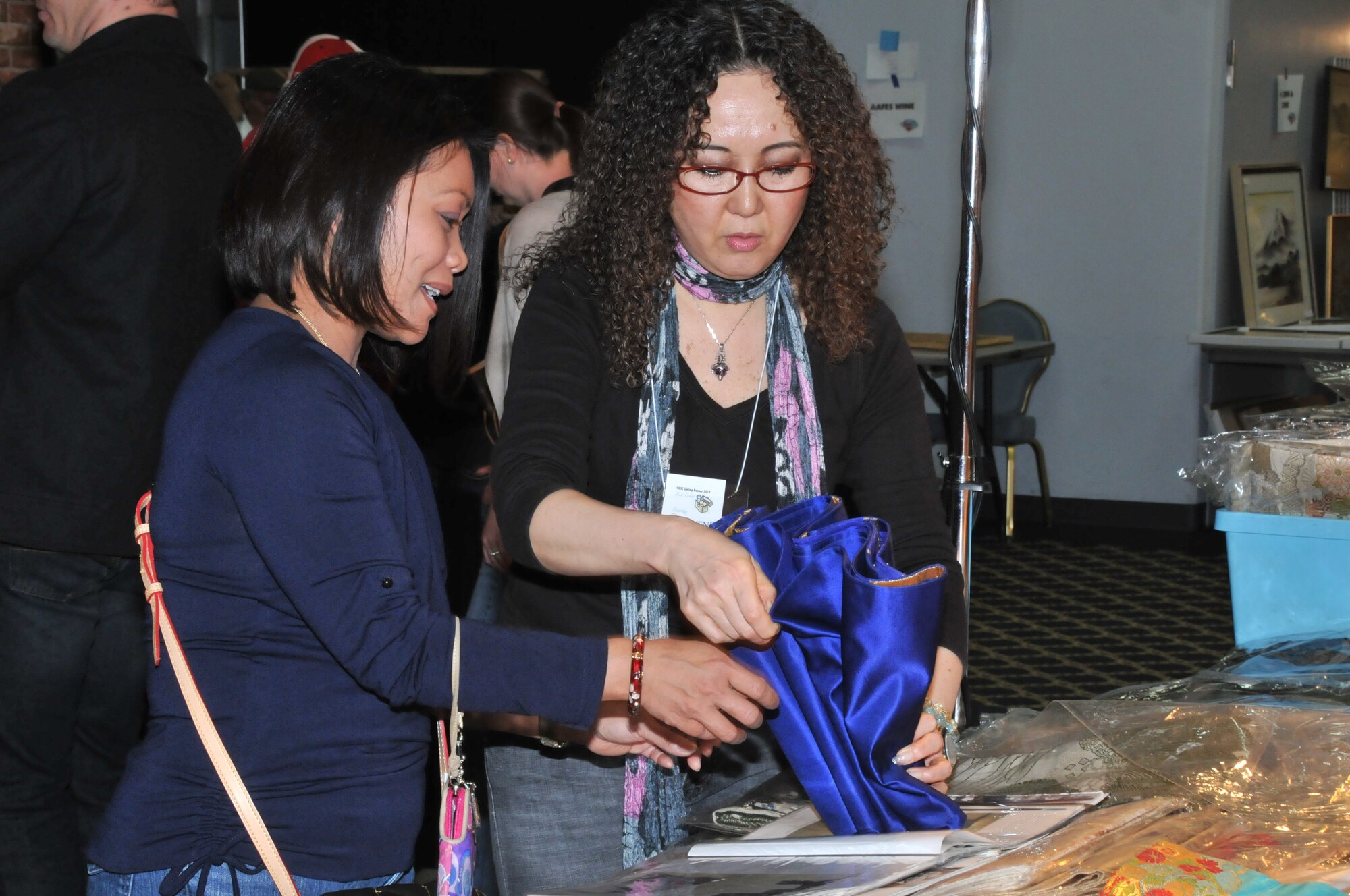 YOKOTA AIR BASE, Japan -- Helen Martinez learns to fold a decorative obi from Misuzu Takimoto at the Yokota Officer's Spouse's Club Asian Bazaar at Yokota Air Base, Japan, March 31, 2012. Obis, are traditionally worn with kimonos, but are more recently used as household decorations. (U.S. Air Force photo/Airman 1st Class Desiree Economides)