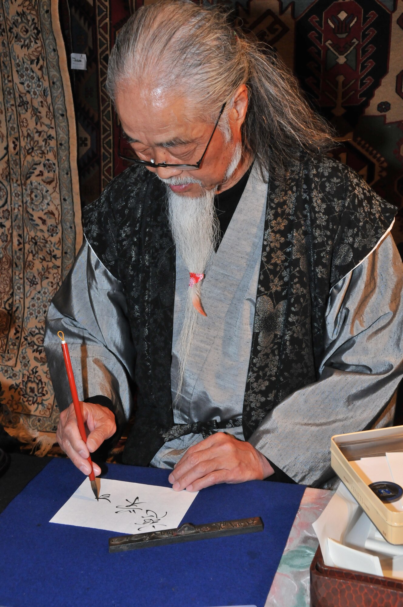 YOKOTA AIR BASE, Japan -- Wako Hachiyo, kanji artist, writes kanji using a calligraphy pen at the Yokota Officer's Spouse's Club Asian Bazaar, March 31, 2012, at Yokota Air Base, Japan. The YOSC sponsors two bazaars a year, which benefit go to scholarships for the community. (U.S. Air Force photo/Airman 1st Class Desiree Economides)