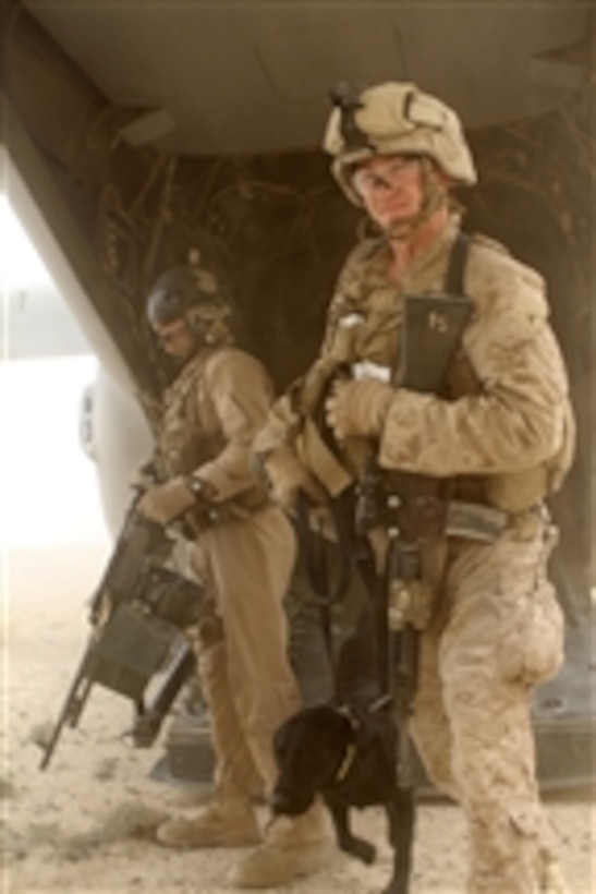 U.S. Marine Corps Sgt. Kyle Harrison (right), a crew chief with Marine Medium Tiltrotor Squadron 365, stands watch as Marines with the 2nd Battalion, 6th Marine Regiment and Bone, a military working dog, disembark an MV-22B Osprey aircraft in Helmand province, Afghanistan, on March 28, 2012.  