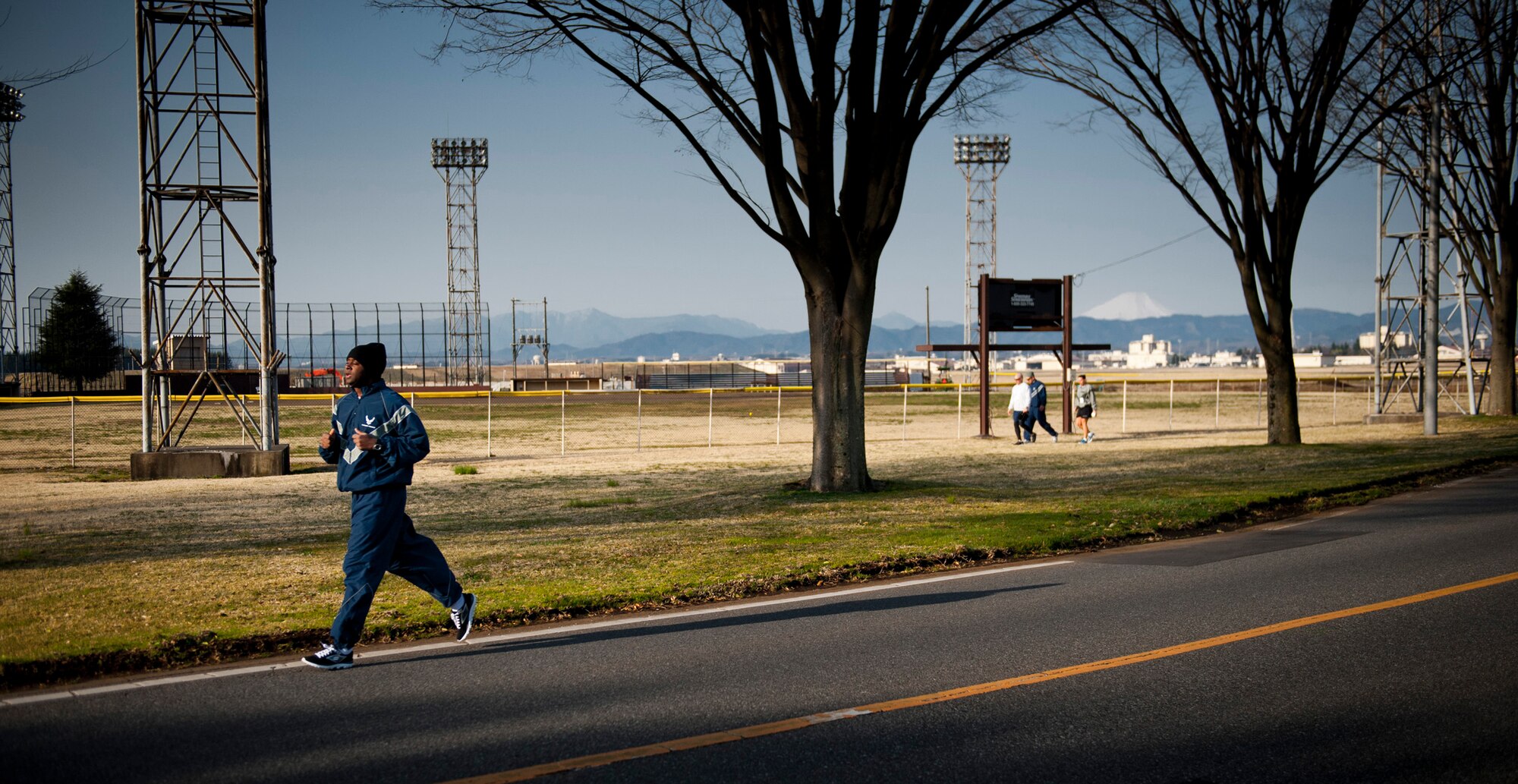YOKOTA AIR BASE, Japan -- A jogger runs along a road blocked off for the Sexual Assault Awareness Month 5K relay at Yokota Air Base, Japan, April 2, 2012. In the distance, Mt. Fuji towers over the surrounding terrain with its snow-capped peak. (U.S. Air Force photo/Staff Sgt. Samuel Morse)