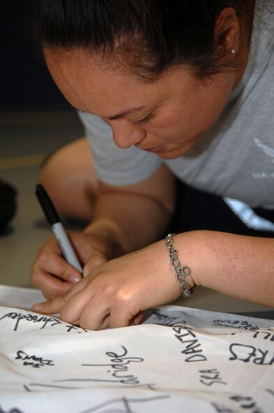 Airmen sign a U.S. Olympic banner during the kickoff of the Air Force Global Strike Command American 300 Never Quit Series Rowing Challenge at the fitness center on Barksdale Air Force Base, La. April 5. The banner will go to the U.S. Olympic row team in support of the summer games held in London. (U.S. Air Force photo/Airman 1st Class Joseph A. Pagán Jr.)(RELEASED)