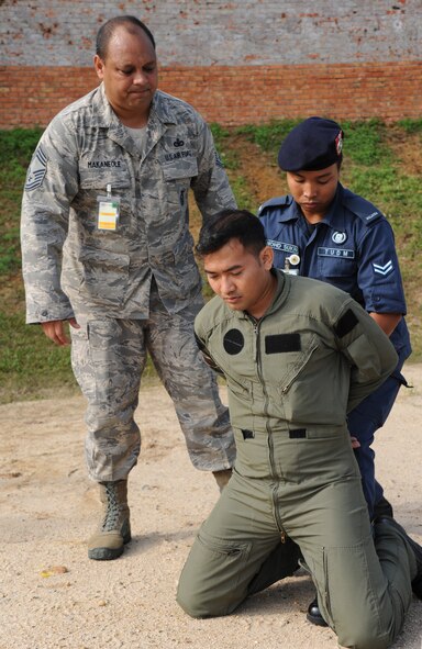 Chief Master Sgt. William Makaneole, Pacific Air Forces plans and programs project officer, watches as Royal Malaysian Air Force Cpl. Mohd Sukri Bin Nor Saidi, Provost Squadron 104, searches a simulated suspect during a subject matter expert exchange at Cope Taufan 2012 at TUDM Butterworth Apr. 5, 2012. (U.S. Air Force photo/Master Sgt. Matt Summers/released)
