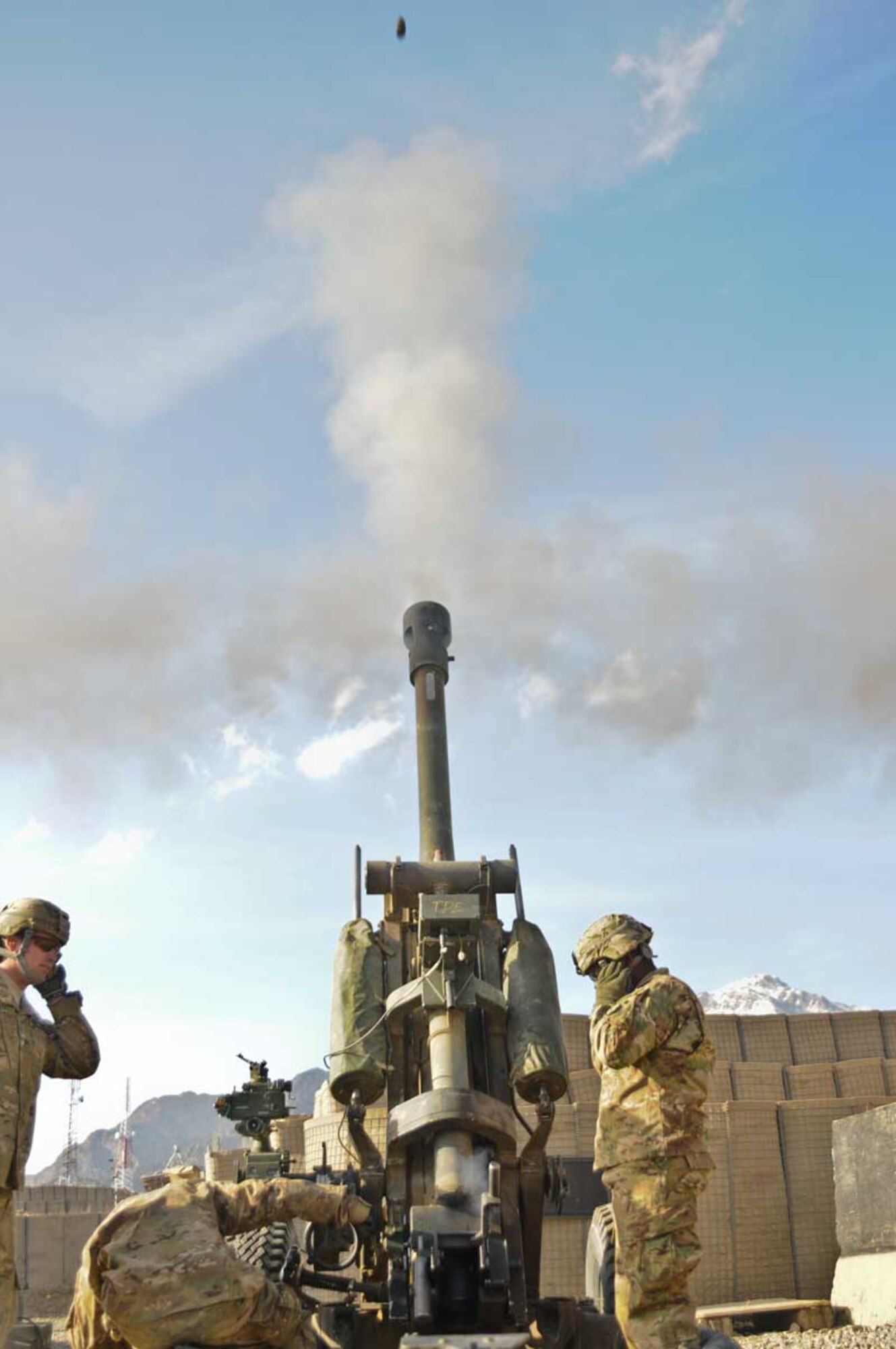 Staff Sgt. Matthew Scott (left), a native of Ventura, Calif., and section chief, Sgt. Philip Nommay, a gunner who hails from Indianapolis, and Pfc. Enos Mowatt, an assistant gunner from Seattle, all assigned to B/2-377th PFAR, fire an M1NC high-explosive round out of a 105-mm howitzer at COP Herrera March 26. (U.S. Army photo/Staff Sgt. Jason Epperson)
