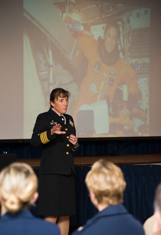 Navy Capt. Heidemarie Stefanyshyn-Piper, Naval Surface Warfare Center Caderock Division commander, addresses a Joint Base Andrews audience during an Andrews Leadership Series event at the Community Activity Center on March 29.  The background photo depicts Capt. Stefanyshyn-Piper serving as an astronaut during the space shuttle Endeavor mission in 2008.  (Photo/Bobby Jones)