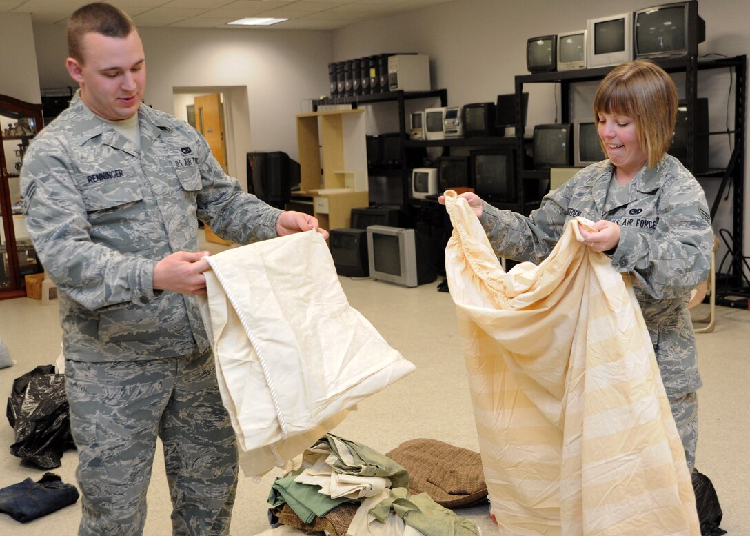 Senior Airmen Harry Renninger and Amy Breeden, 11th Logistics Readiness Squadron vehicle operators, help fold sheets March 30 that were donated to the Andrews Attic in support of families effected by a base housing fire. (U.S. Air Force photo/Senior Airman Laura Turner)
