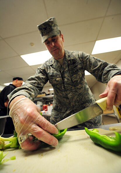 Col. Mike Hill, 92nd Mission Support Group commander, slices up a green bell pepper during the breakfast shift in the Warrior Dining Facility at Fairchild Air Force Base, Wash., March 23, 2012. The colonel will periodically participate in the work his Airmen perform to better understand the effort put into the mission. (U.S. Air Force photo by Airman 1st Class Taylor Curry/Released)