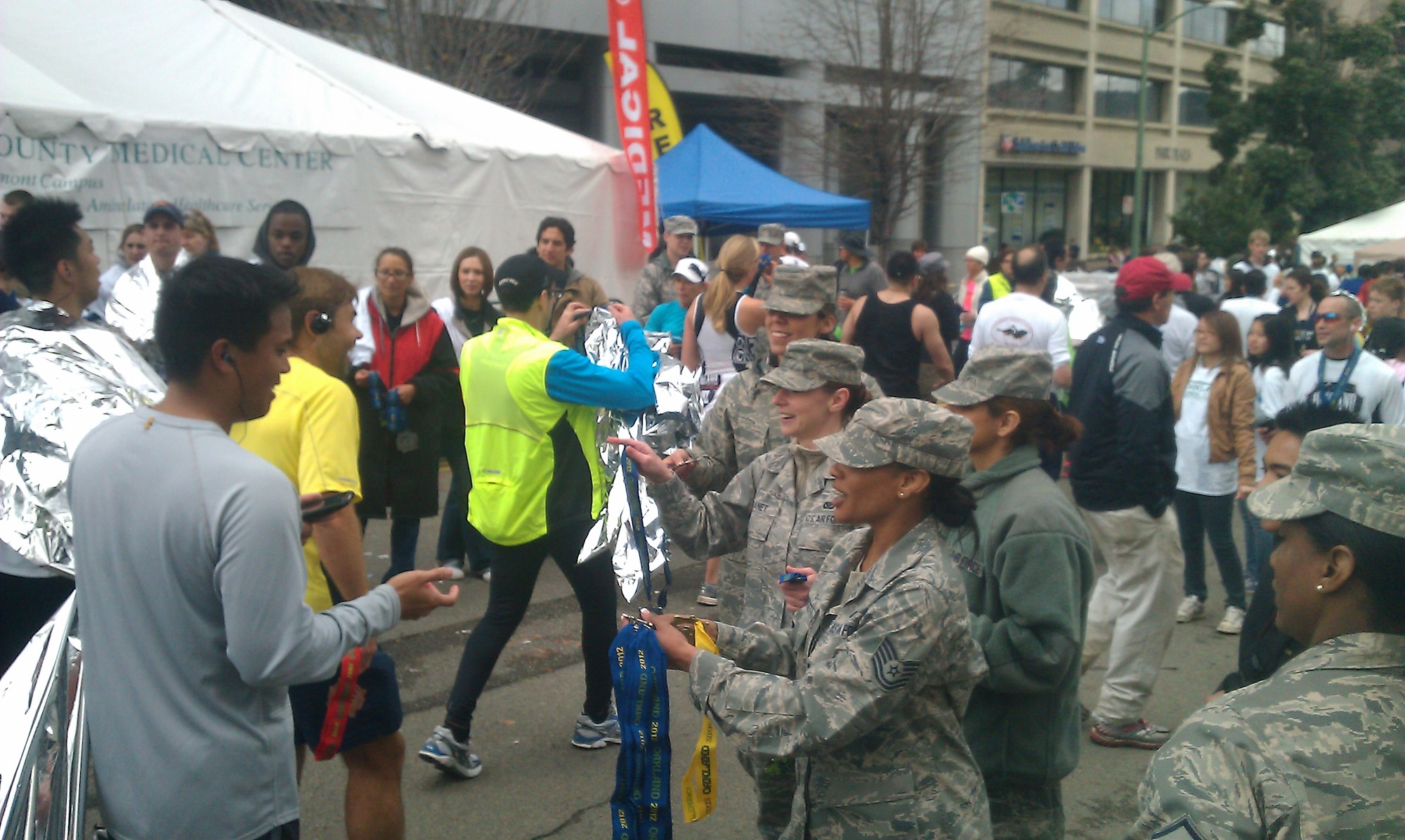 Members of the 364th Recruiting Squadron (l-r)Tech. Sgt. Julianne Lapointe, Staff Sgt.  Melissa Kanet, and Tech. Sgt. LaSandra Crockett) present medals to runners crossing the finish line of the 2012 Oakland Running Festival March 25. The 364th Recruiting Squadron helped raise over $10K for several local charities. Nineteen squadron members also served as race volunteers, and handed out blankets and medals to runner who crossed the finish line. Sixteen squadron members ran the half-marathon and 44 young Americans were sworn into the Delayed Enlistment Program. The DEPper s also volunteered as course marshals, bag checkers, as well as handed out medals and blankets at the running festival. (U.S. Air Force photo/Tech. Sgt. Leo Morales)