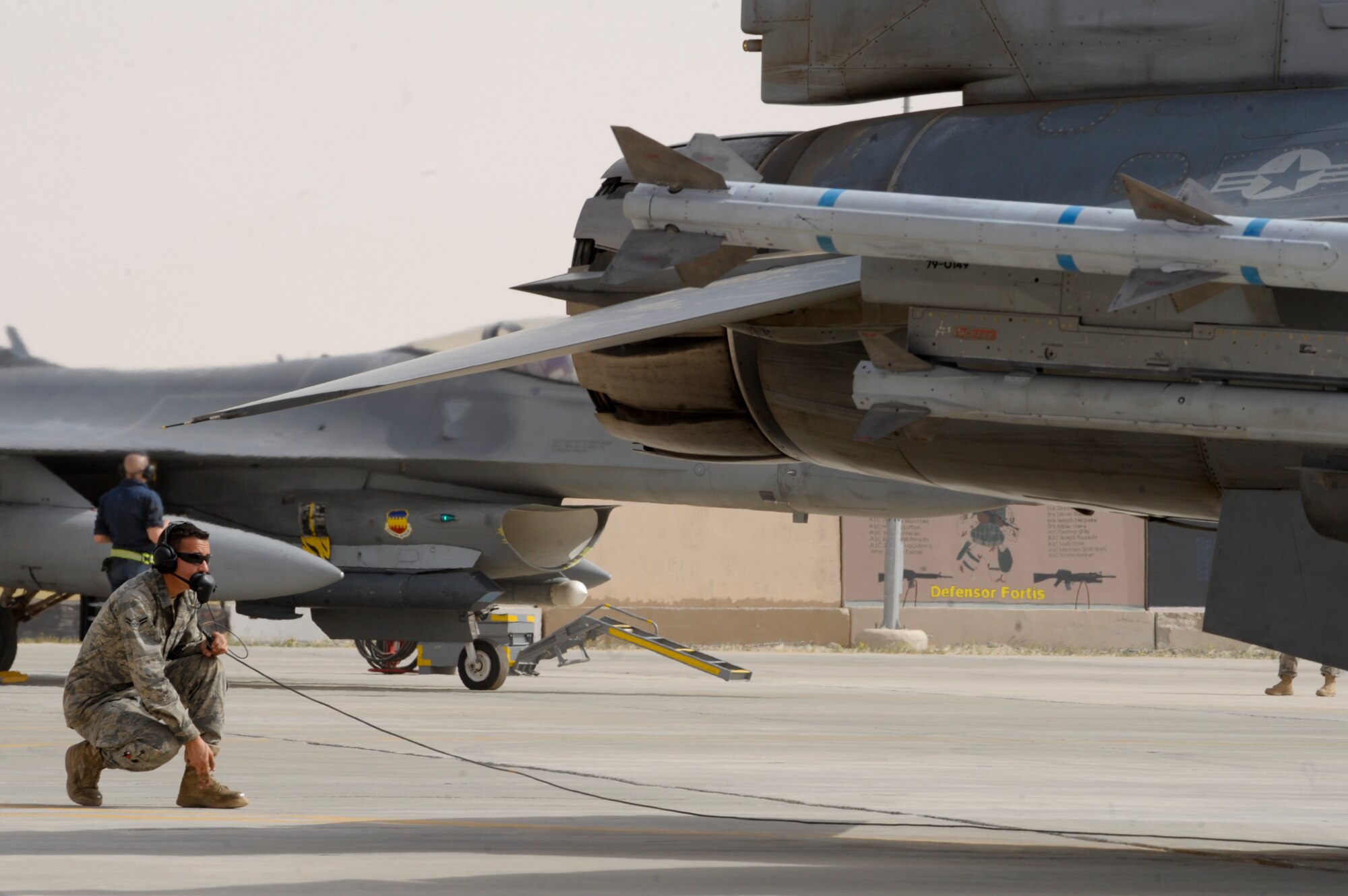 SOUTHWEST ASIA -- Airman 1st Class Justin Glass, 332nd Expeditionary Aircraft Maintenance Squadron crew chief, watches tail fins of an F-16 Fighting Falcon during a preflight inspection here April 3, 2012. Glass communicates with the pilot during the inspection by using hand signals and a radio headset. Glass is deployed from Shaw Air Force Base, S.C. and is a native of Tucson, Ariz. (U.S. Air Force photo by Staff Sgt. Joshua J. Garcia