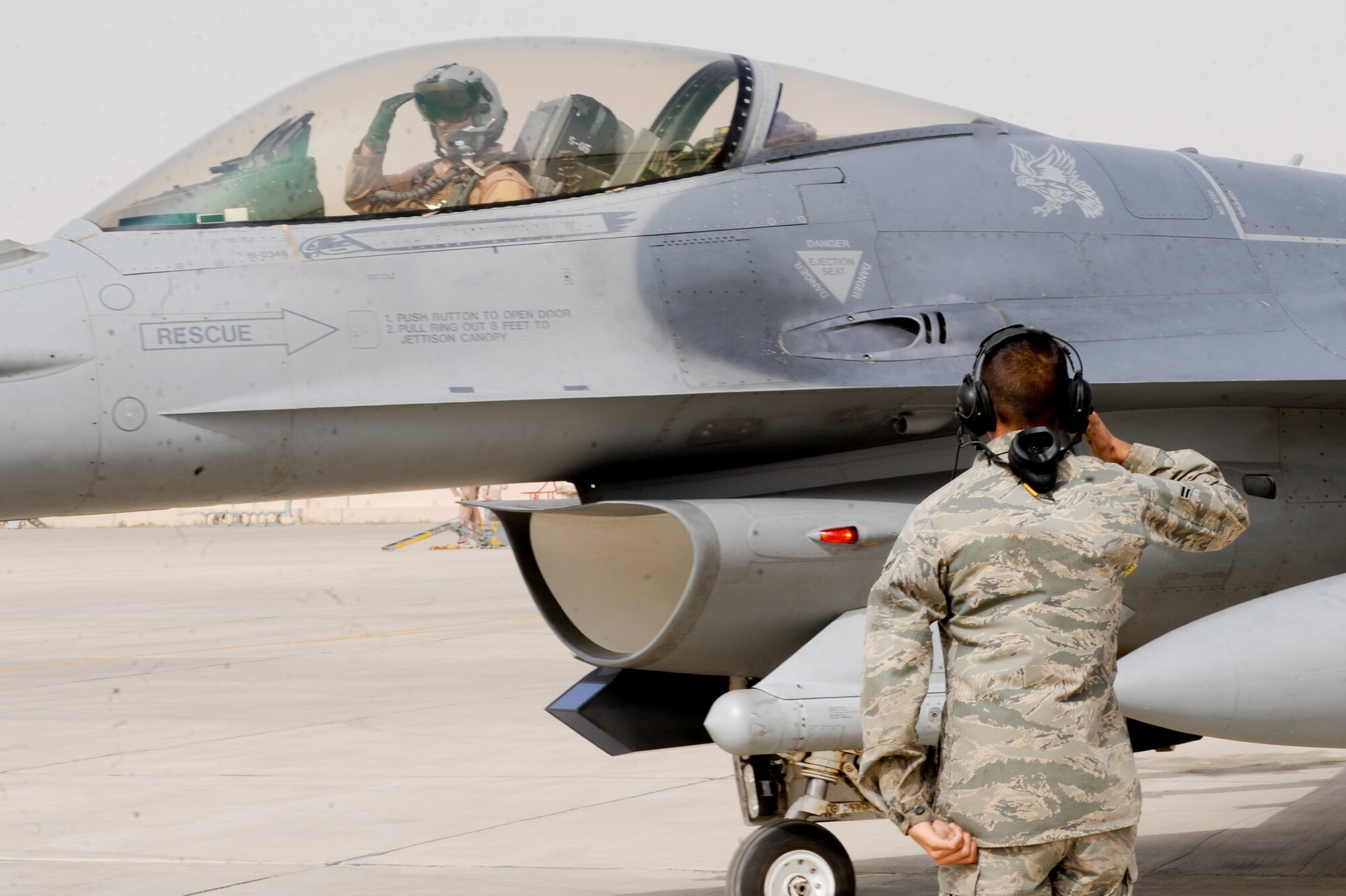 SOUTHWEST ASIA -- Col. Rodney Petithomme, 332nd Expeditionary Operations Group commander, receives a salute from Airman 1st Class Justin Glass, 332nd Expeditionary Aircraft Maintenance Squadron, prior to taxiing here April, 3 2012. Crew chiefs and pilots work together during preflight procedures to complete aircraft function checks. Petithomme is deployed from Osan Air Base, Korea, and is a native of Clovis, Calif. Glass is deployed from Shaw Air Force Base, S.C. and is a native of Tucson, Ariz. (U.S. Air Force photo by Staff Sgt. Joshua J. Garcia)