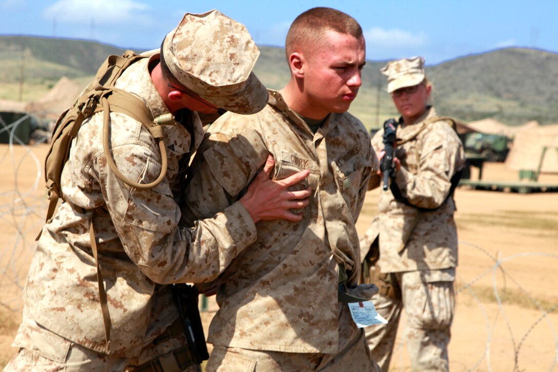 Lance Cpl. Sidney B. Ward pats down Lance Cpl. William E. Curry, who is acting as a detainee, as Lance Cpl. Alecia R. Mesch provides security during a simulated in-processing at the detention center built as a part of Military Police training during Marine Expeditionary Unit Exercise, here, April 5. The construction of the facility took the Marines an entire day. It includes two large working tents, two large metal storage containers and six pallets of concertina wire, all for a training facility half the size of one they would build if called to shore. Curry, 20, is a native of Philadelphia. Ward, 20, is a native of Dardonelle, Ark. Mesch, 20, is a native of Denver. They are all field MPs with the MP detachment, Combat Logistics Battalion 15, 15th MEU.