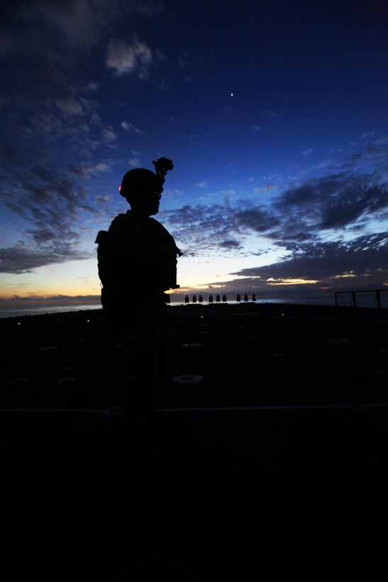 A Marine with Charlie Company, Battalion Landing Team 1st Battalion, 2nd Marine Regiment, 24th Marine Expeditionary Unit, watches the sun disappear beyond the Atlantic Ocean while waiting to begin nighttime live-fire training on the ship’s flight deck, April 5, 2012. The 24th MEU, partnered with the Navy's Iwo Jima Amphibious Ready Group, is deploying to the European and Central Command theaters of operation to serve as a theater reserve and crisis response force capable of a variety of missions from full-scale combat operations to humanitarian assistance and disaster relief.