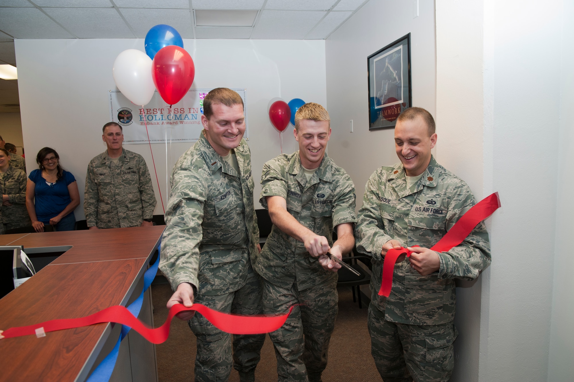 2nd Lt. Tyson Kempton, Force Management officer in charge; Airman 1st Class Kenneth Reininger, 49th Force Support Squadron manpower journeyman and Major Christopher Busque, 49th FSS commander, cut the ribbon April 6 during the Military Personnel Squadron grand opening ceremony. Members of Team Holloman came together to commemorate the grand opening ceremony of the newly renovated 49th MPS. The $244,000 renovation, which was funded directly by the U.S. Air Force, began in February. (U.S. Air Force photo by Senior Airman DeAndre Curtiss / Released) 