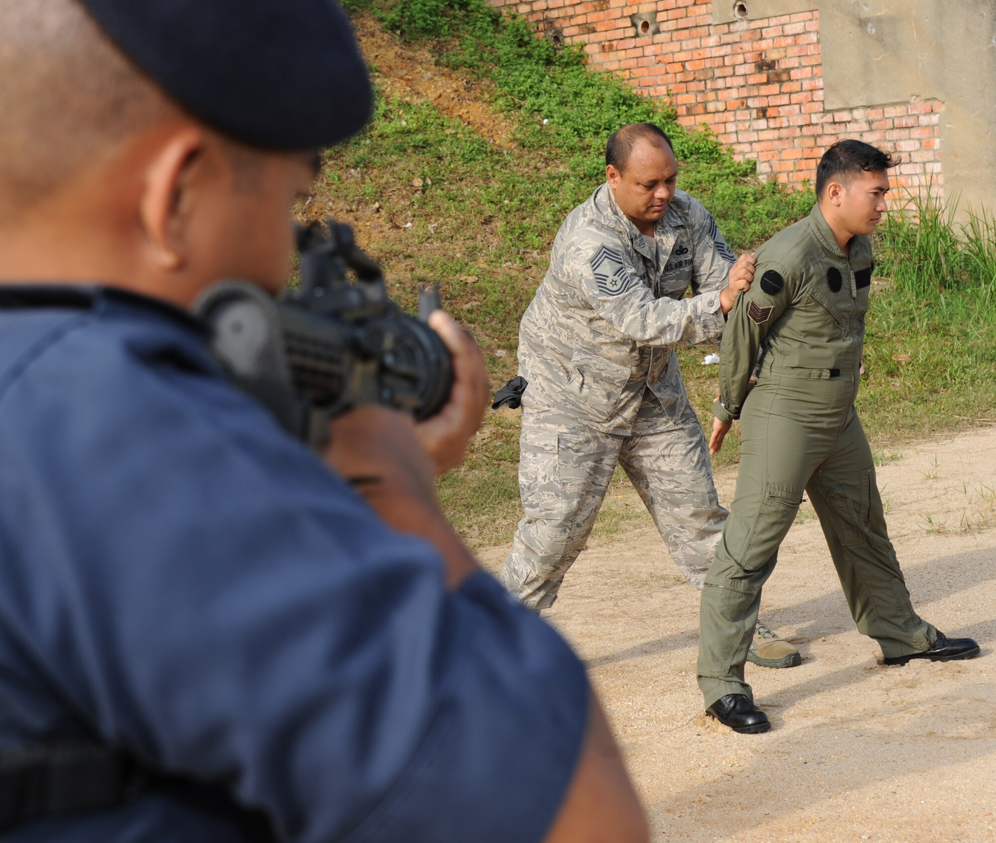 Chief Master Sgt. William Makaneole, a Pacific Air Forces plans and programs project officer, shows Royal Malaysian Air Force airmen from Provost Squadron 104 how to search a simulated suspect during a subject matter expert exchange at Cope Taufan 2012 at TUDM Butterworth on April 5, 2012. (U.S. Air Force photo/Master Sgt. Matt Summers)