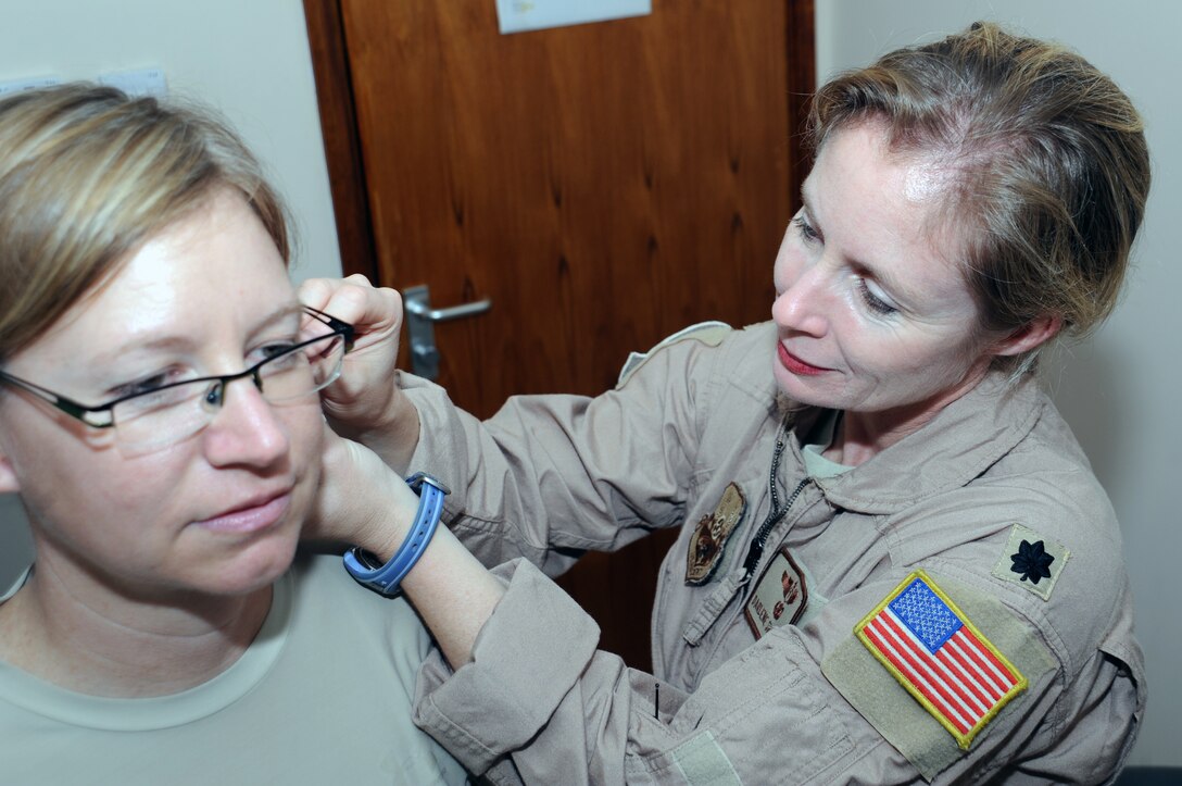 SOUTHWEST ASIA - Lt. Col. (Dr.) Darlene Smallman applies acupuncture needles to Maj. Amber Hirsch's ear April 4, 2012. Hirsch suffers from hip pain and has found acupuncture the only treatment that helps her. Smallman, a flight surgeon deployed to the 380th Air Expeditionary Wing from the Pentagon, studied at the Air Force Acupuncture Center on Joint Base Andrews, Md. Hirsch is the wing judge advocate. (U.S. Air Force photo/Staff Sgt. J.G. Buzanowski)