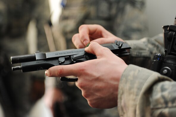 U.S. Air Force Airman 1st Class Alec Foor, 35th Security Forces Squadron defender, puts a 550 cord into his M-9 pistol during High Risk Response Training at Misawa Air Base, Japan, March 30, 2012. The 550 cord is inserted into the pistol as a training tool to allow everyone to know that the weapon is clear of ammunition. Regular training exercises like this, gave 35 SFS Airmen the ability to develop the skills and knowledge that resulted in the squadron earning the Air Force Outstanding Security Forces Medium Unit 2011. (U.S. Air Force photo/Airman 1st Class Kia Atkins/Released) 

