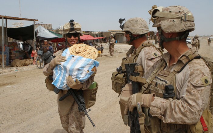 Corporal Ricardo J. Figueroa, an electrician and noncommissioned officer in charge of Marine Corps Integrated Maintenance Management System serving with Utilities Platoon, Regimental Combat Team 5, volunteers to carry bread purchased at a bazaar during a patrol here, April 6, 2012. Colonel Roger Turner and Sgt. Maj. Alberto Ruiz, the RCT-5 commanding officer and sergeant major, visited Marines and Afghan National Security Forces at several combat outposts throughout Helmand province’s Marjah district. Figueroa, a Temecula, Calif., native, made rounds to every generator at each post to inspect and ensure they were in proper working order.