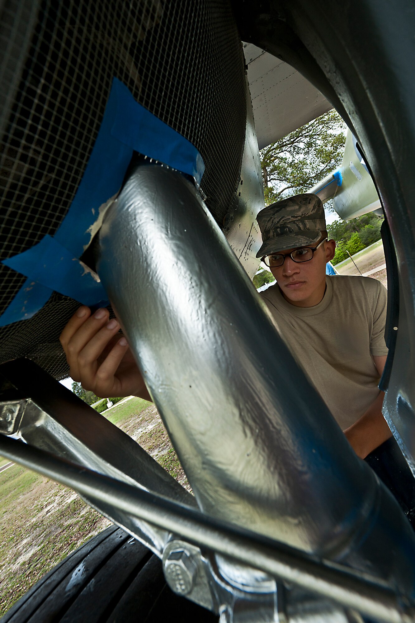 Airman 1st Class Anthony Colon-Matos, of the 96th Logistics Readiness Squadron, removes the painters tape off of the B-25 aircraft display at the Air Force Armament Museum, April 5.  Colon-Matos and other members of LRS’s petroleum, oil and lubricants flight restored the B-25 as part of Eglin’s Adopt-a-Plane program.  LRS adopted the B-25 six years ago.  This is the second time the squadron’s Airmen have painted it.  (U.S. Air Force photo/Samuel King Jr.)