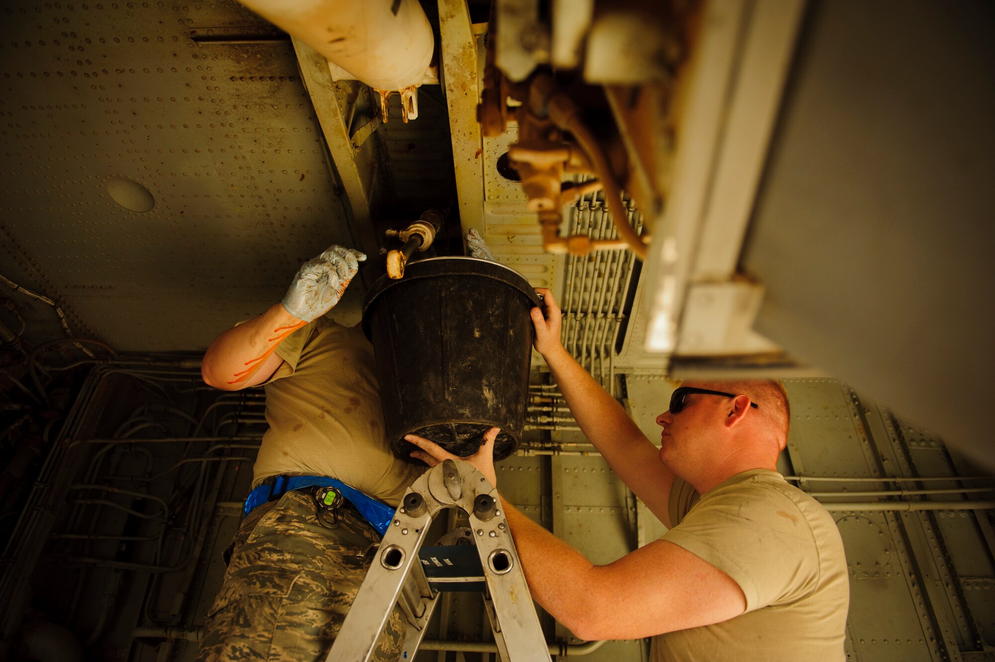 SOUTHWEST ASIA – Airman 1st Class Johnathan Holmes and Tech. Sgt. Adam Jensen, 340th Expeditionary Aircraft Maintenance Unit hydraulics specialists, let a hydraulic line drain on the side strut actuator for the main landing gear on a KC-135 Stratotanker here April 4. Jensen, who has been a hydraulics specialist on the KC-135 for ten years, used the broken actuator as an opportunity to accomplish some on-the-job training for Holmes. (U.S. Air Force photo/Staff Sgt. Nathanael Callon)