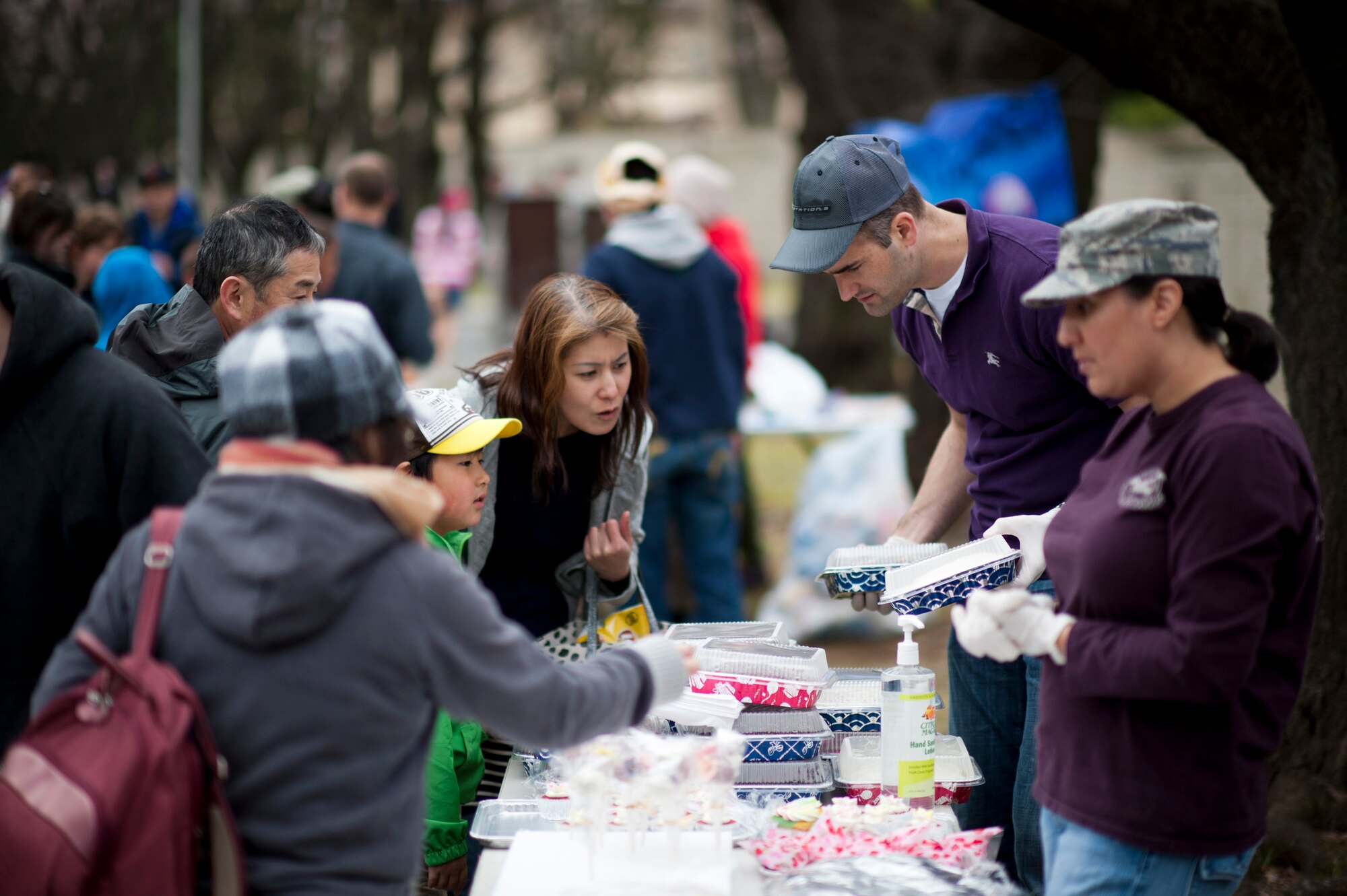 YOKOTA AIR BASE, Japan -- Lt. Col. James Hackbarth (center-right), 374th Operations Support Squadron commander, shows different home-baked cakes to Japanese visitors at Yokota Air Base, Japan, April 7, 2012. Yokota officials opened the eastern gate of the base to allow local community members to view the cherry blossom trees along McGuire Avenue. (U.S. Air Force photo/Staff Sgt. Samuel Morse)
