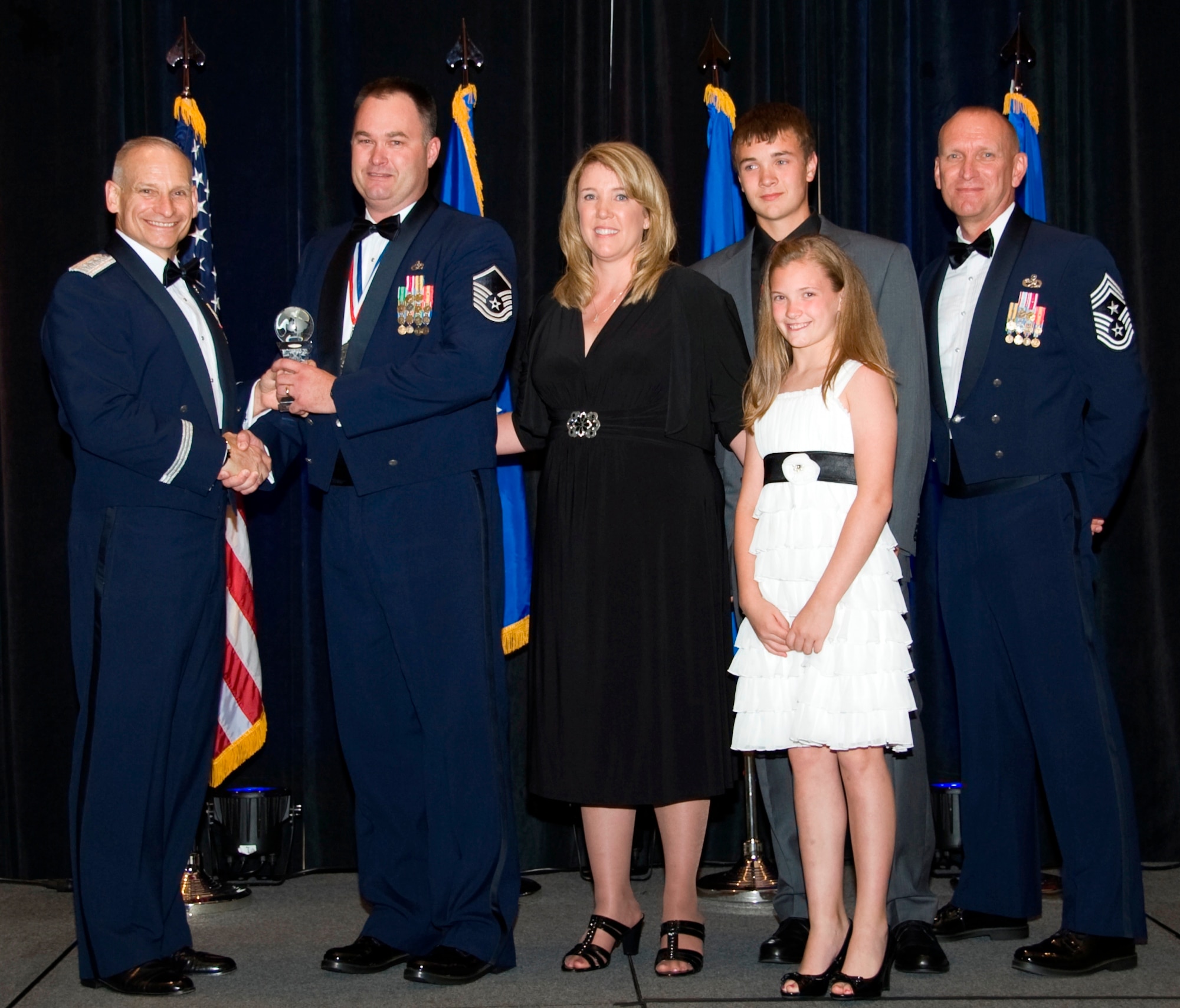 Master Sgt. Keith Lockard, heavy repair superintendent, 509th Bomb Wing, accompanied by his family, receives Air Force Global Strike Command Outstanding Senior Non-Commissioned Officer of the Year from Lt. Gen. Kowalski, commander AFGSC, and Chief Master Sgt. Brian Hornback, AFGSC command chief here April 5. (U.S. Air Force photo by Airman 1st Class Benjamin Gonsier)