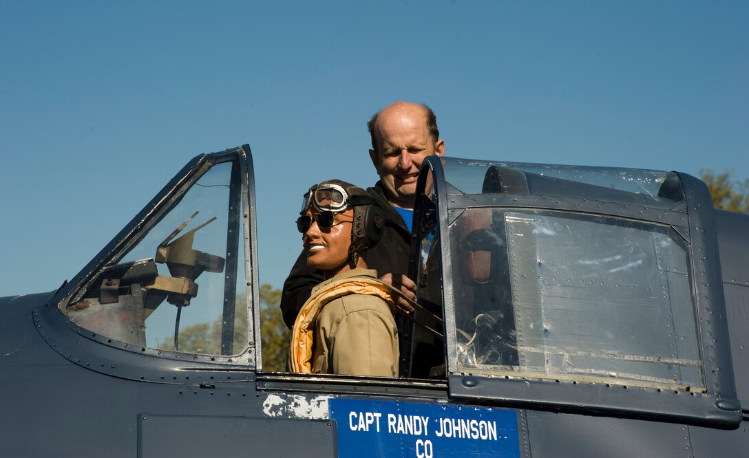 Tech. Sgt. Daniel Glessner, 459th Air Refueling Wing machinist, completes his six-month upgrade project on his robotic mannequin, as he straps Admiral Brian Glessner into the cock pit of a vintage Navy Gruman F6F-5K Hellcat aircraft on display near the Naval Air Facility Washington entrance.  (Photo/Bobby Jones)
