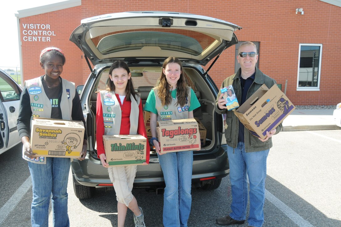 From left, Charis Nelson, Amelia Peterson (left) and Alexis Nelson, from Girl Scout Troop 12109, deliver Girl Scout cookies to Mike Sanford, 934th Airlift Wing director of Airmen and Family Readiness. The cookies will be given to deploying Airmen from the 934th Airlift Wing. (Air Force Photo/Paul Zadach)