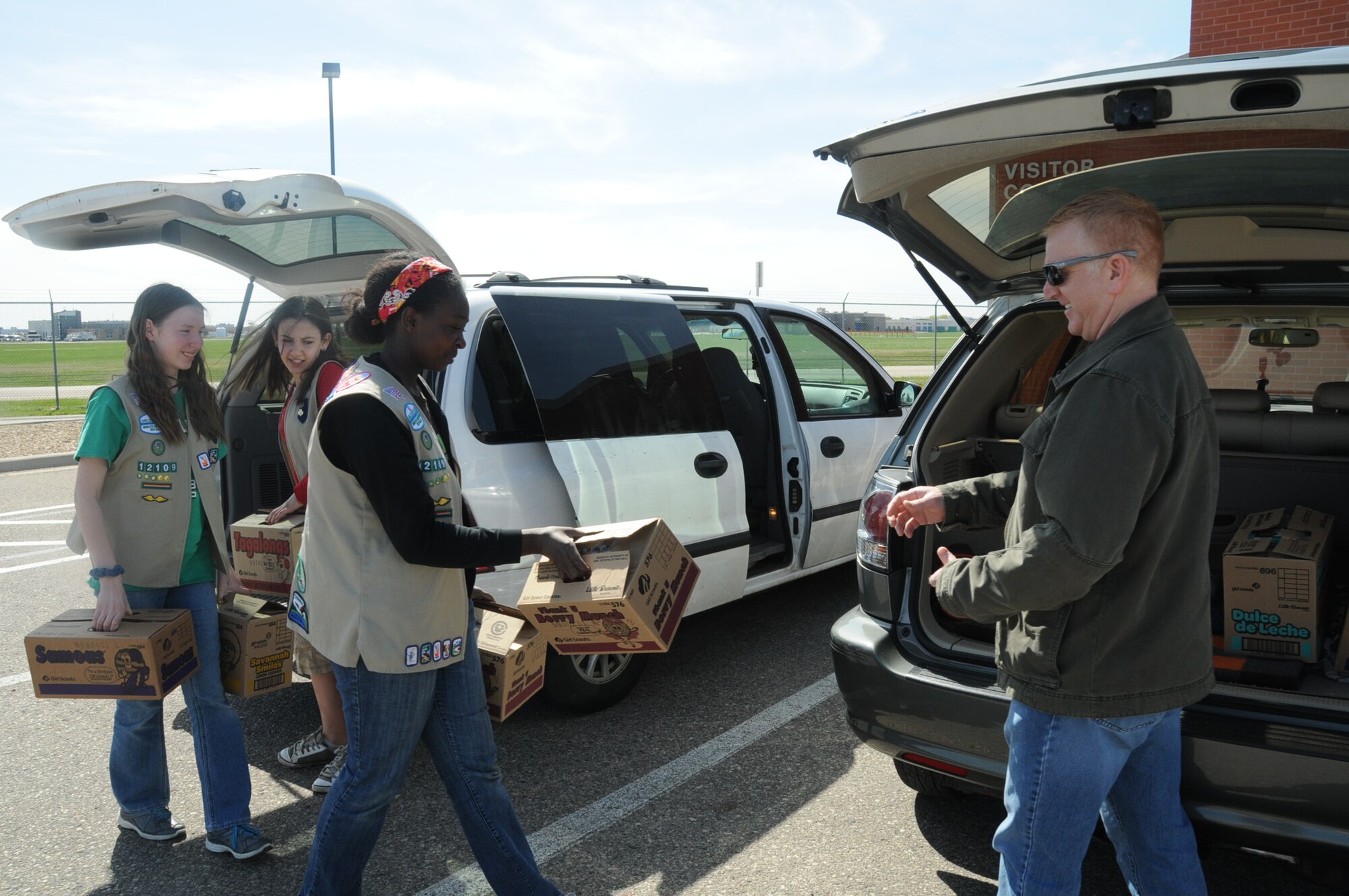 From left, Alexis Nelson, Amelia Peterson and Charis Nelson, from Girl Scout Troop 12109, deliver Girl Scout cookies to Mike Sanford, 934th Airlift Wing director of Airmen and Family Readiness. The cookies will be given to deploying Airmen from the 934th Airlift Wing. (Air Force Photo/Paul Zadach)