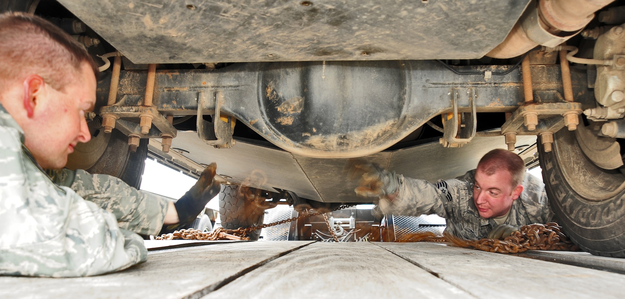 WHITEMAN AIR FORCE BASE, Mo. – Tech. Sgt. Jacob A. Byers, 509th Logistics Readiness Squadron NCO in charge of equipment support, and Staff Sgt. Christopher Waters, 509th Logistics Readiness Squadron vehicle trainer, chain down a government vehicle March 23. To prevent accidents and damage to the vehicle being carried, they are chained down when being transported from one location to the next. (U.S. Air Force photo/Senior Airman Nick Wilson)