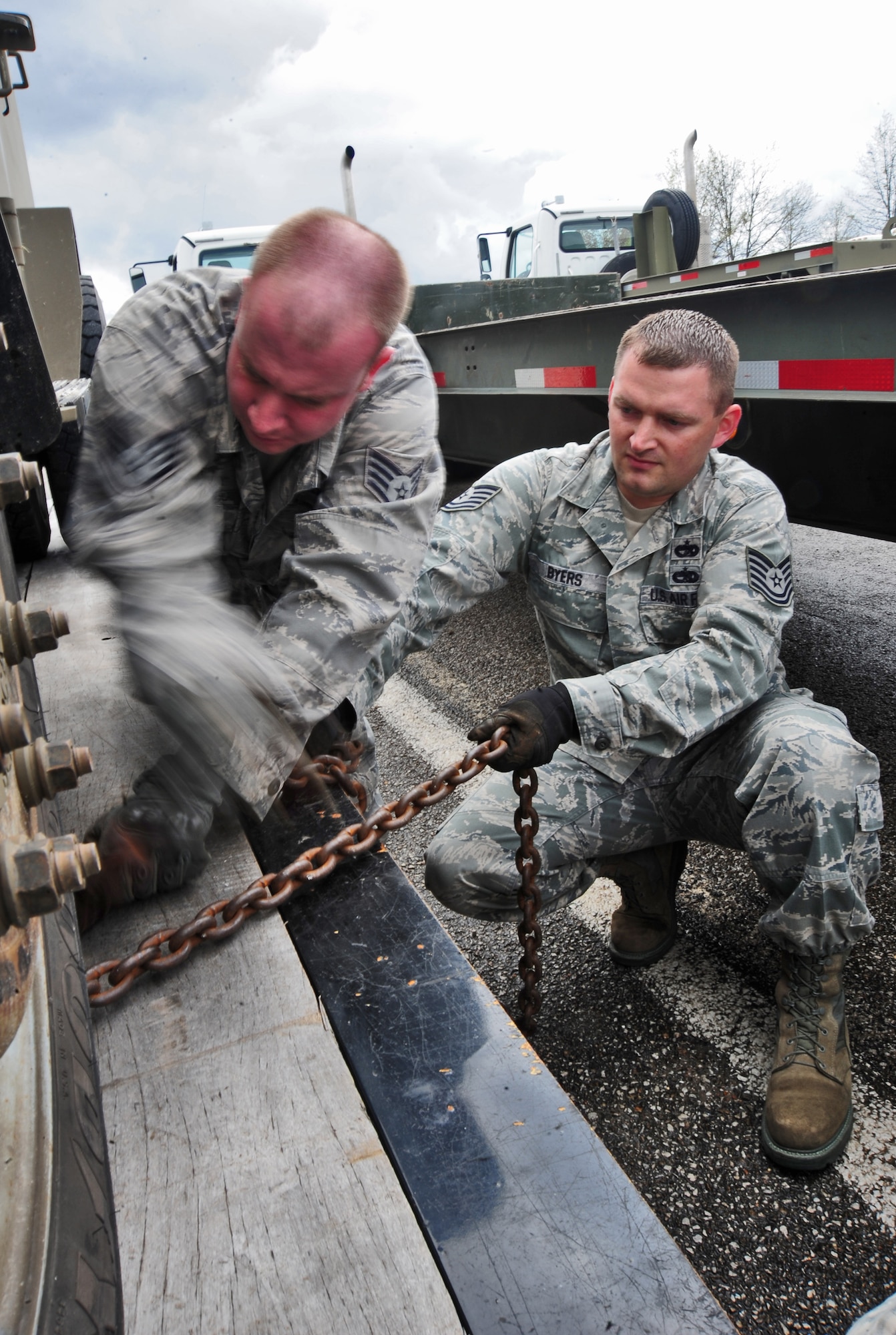 WHITEMAN AIR FORCE BASE, Mo. – Staff Sgt. Christopher Waters, 509th Logistics Readiness Squadron vehicle trainer, and Tech. Sgt. Jacob A. Byers, 509th Logistics Readiness Squadron NCO in charge of equipment support, chain down a government vehicle March 23. The chain prevents the vehicle from rolling off the trailer during travel, thus preventing damage to the vehicle, trailer and other drivers. (U.S. Air Force photo/Senior Airman Nick Wilson)
