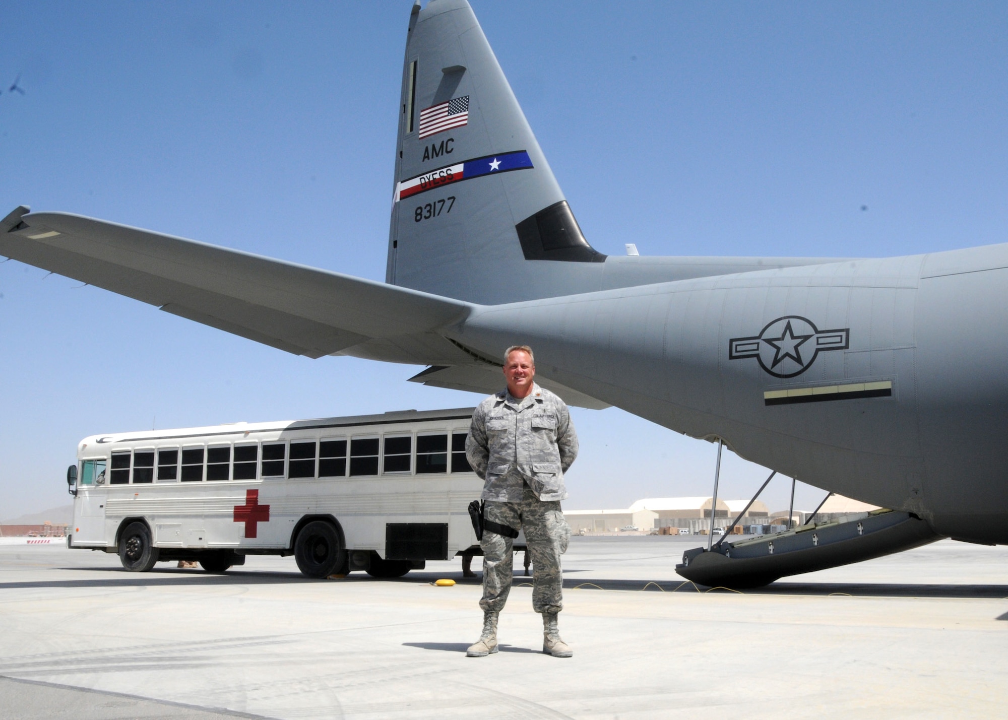 Maj. Peter Jorgensen, 651st Expeditionary Aeromedical Evacuation Squadron, Kandahar Airfield, Afghanistan, director of operations in front of a medical bus and C-130 Hercules aircraft, April 6, 2012. Jorgensen is deployed from the 446th Aeromedical Evacuation Squadron, McChord Field, Wash. His role as 651st EAES director of operations is overseeing the daily duties of more than 100 people, who support around-the-clock aeromedical evacuations for more than 100,000 NATO troops. (U.S. Air Force photo/Staff Sgt. Heather Skinkle)