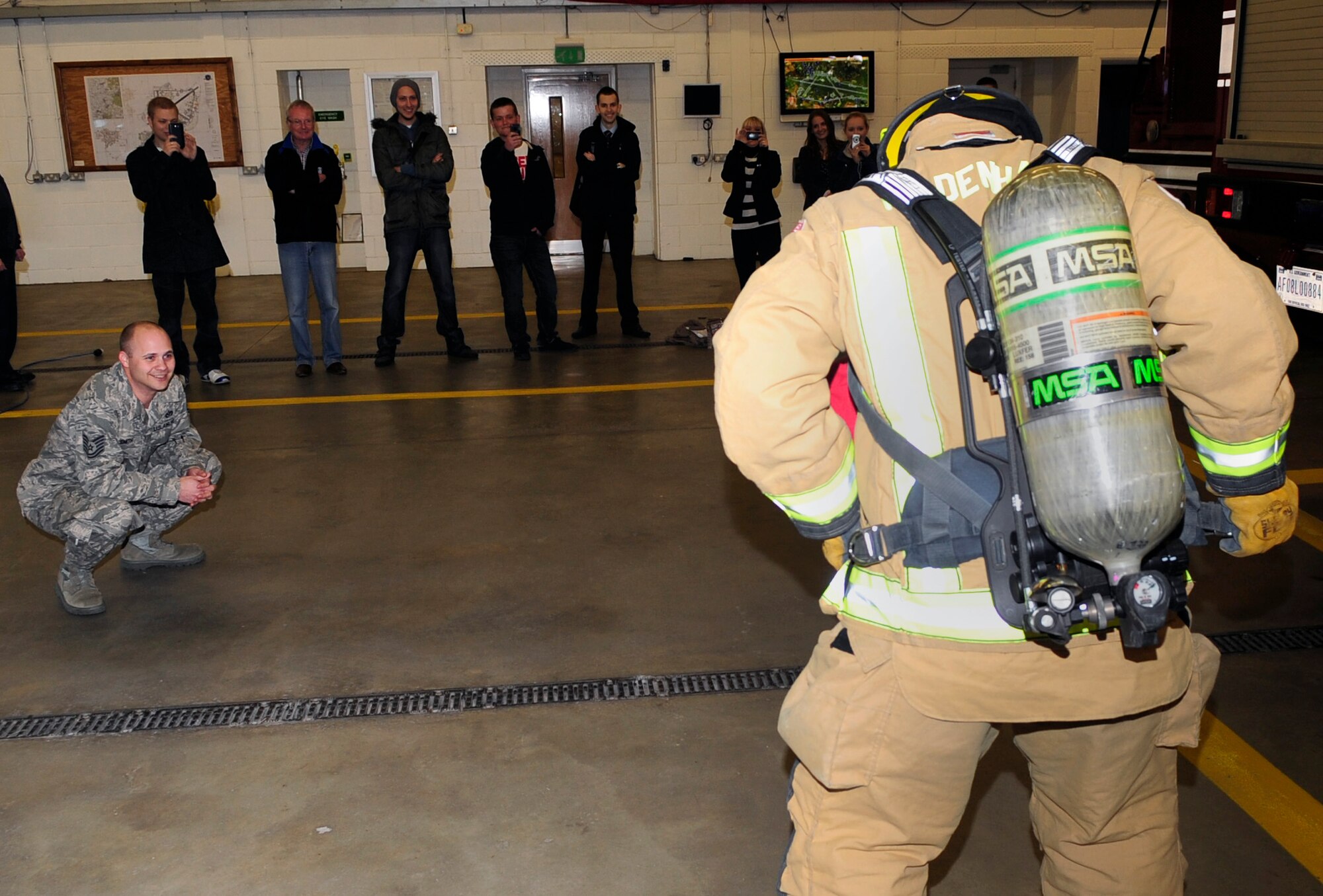RAF MILDENHALL, England -- Members of the Teenage Cancer Trust watch as Airman 1st Class Theodore Willis, 100th Civil Engineer Squadron firefighter, performs a “bunker drill” during a tour of the fire department here April 4, 2012. A bunker drill is a timed test that requires the firefighter to put on all their structural firefighting gear in less than a minute. (U.S. Air Force photo/Senior Airman Ethan Morgan)