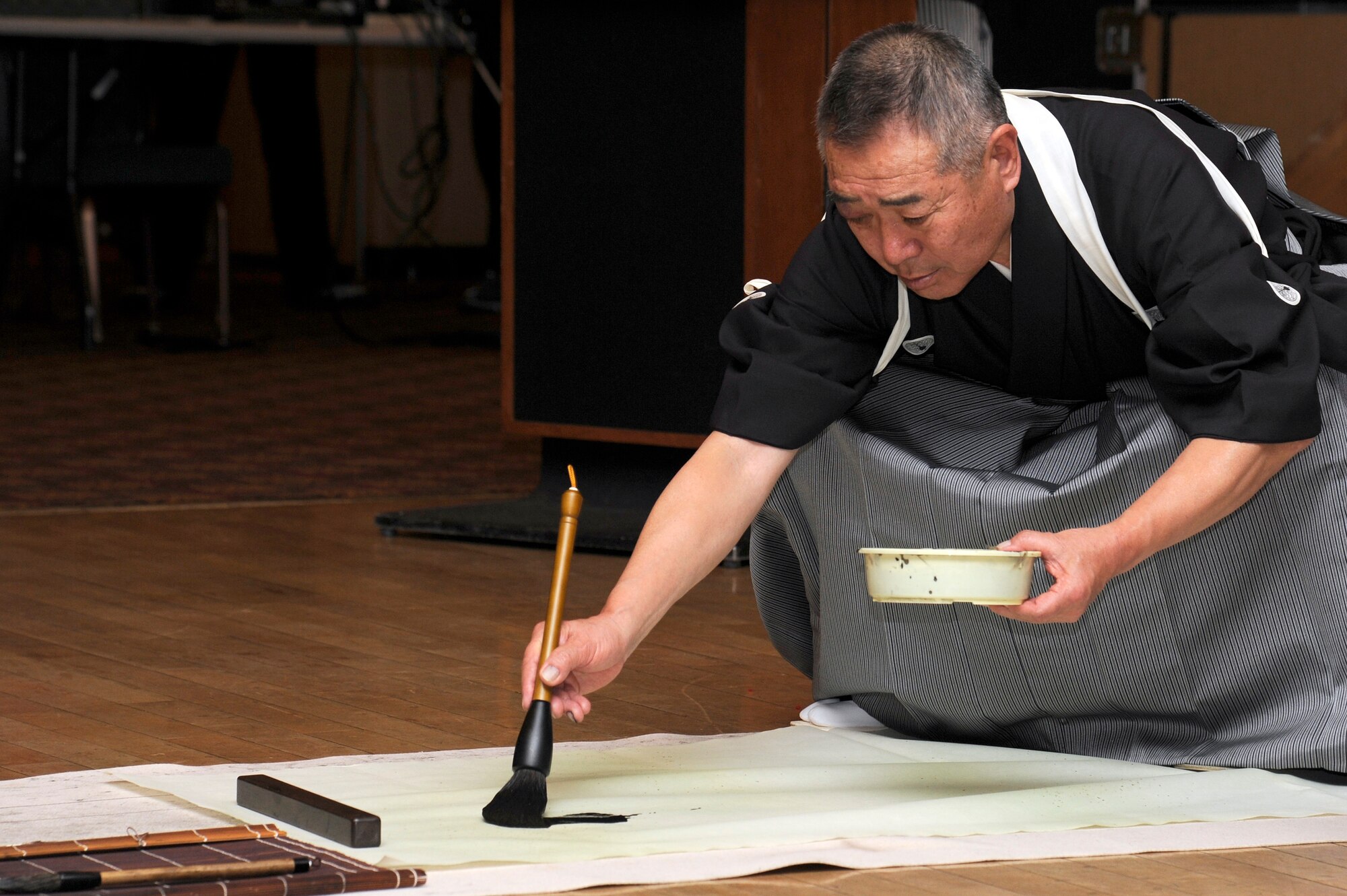 Mr. Takao Sasaki paints Kanji characters representing "bond" for both Misawa City and Misawa Air Base during the 25th Annual Japan Day opening ceremony at Misawa Air Base, Japan, April 7, 2012. Writing a short phrase in Kanji was one of the many cultural displays attendee's had the opportunity to take advantage of during the one-day event. (U.S. Air Force photo by Tech. Sgt. Marie Brown/Released)
