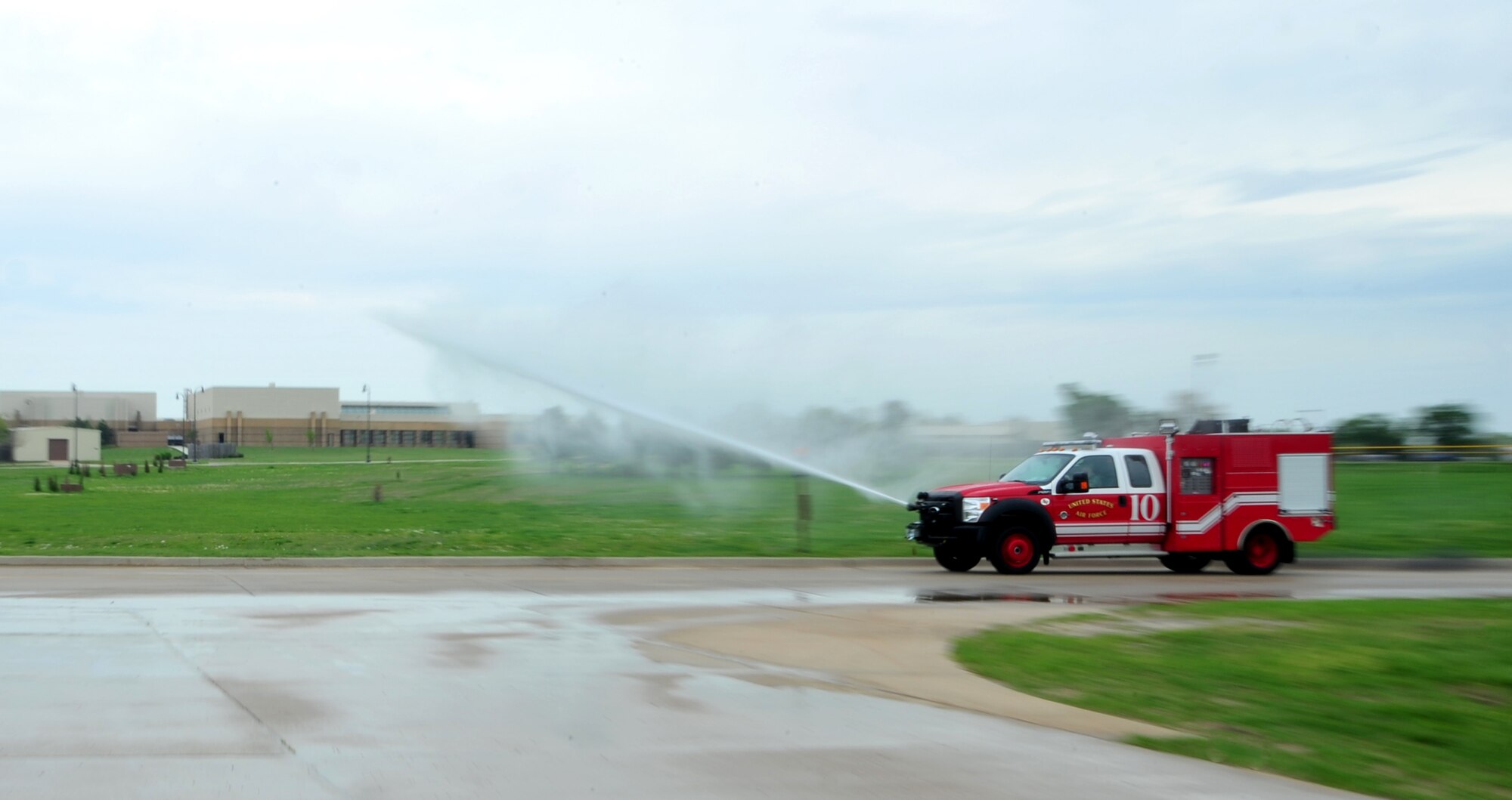 22nd Civil Engineer Squadron firefighters drive a P-34 Rapid Intervention Vehicle while it discharges water from a bumper-mounted ultra high pressure firefighting technology turret April 3, 2012, McConnell Air Force Base, Kan. The turret discharges 100 gallons of firefighting agent per minute at 1,350 pounds per square inch at a range of 100 feet. (U.S. Air Force photo/Staff Sgt. Maria Ruiz)