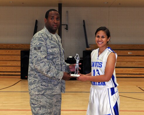 U.S. Air Force Senior Airman Mackeil Wilkes, 355th Force Support Squadron fitness specialist, presents the 3-point shootout trophy to Liezl-Anne Sarte after the 3-point shootout halftime event of the Battle of the Sexes game on Davis-Monthan Air Force Base, Ariz. April 6, 2012. Sarte beat three male contestants to win the 3-point shootout. (U.S. Air Force photo by Airman 1st Class Timothy D. Moore/Released)